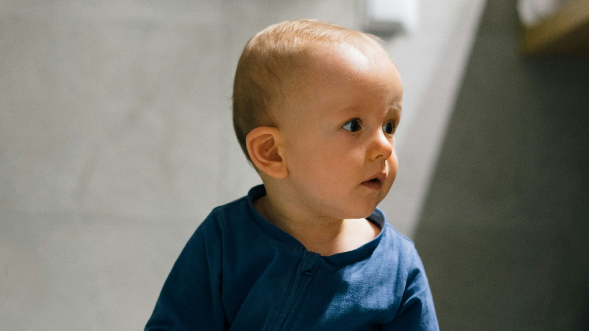 baby in blue long sleeve shirt and blue denim jeans sitting on floor