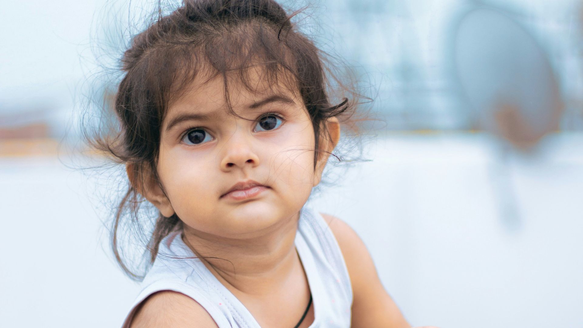 girl in white tank top sitting on brown wooden chair