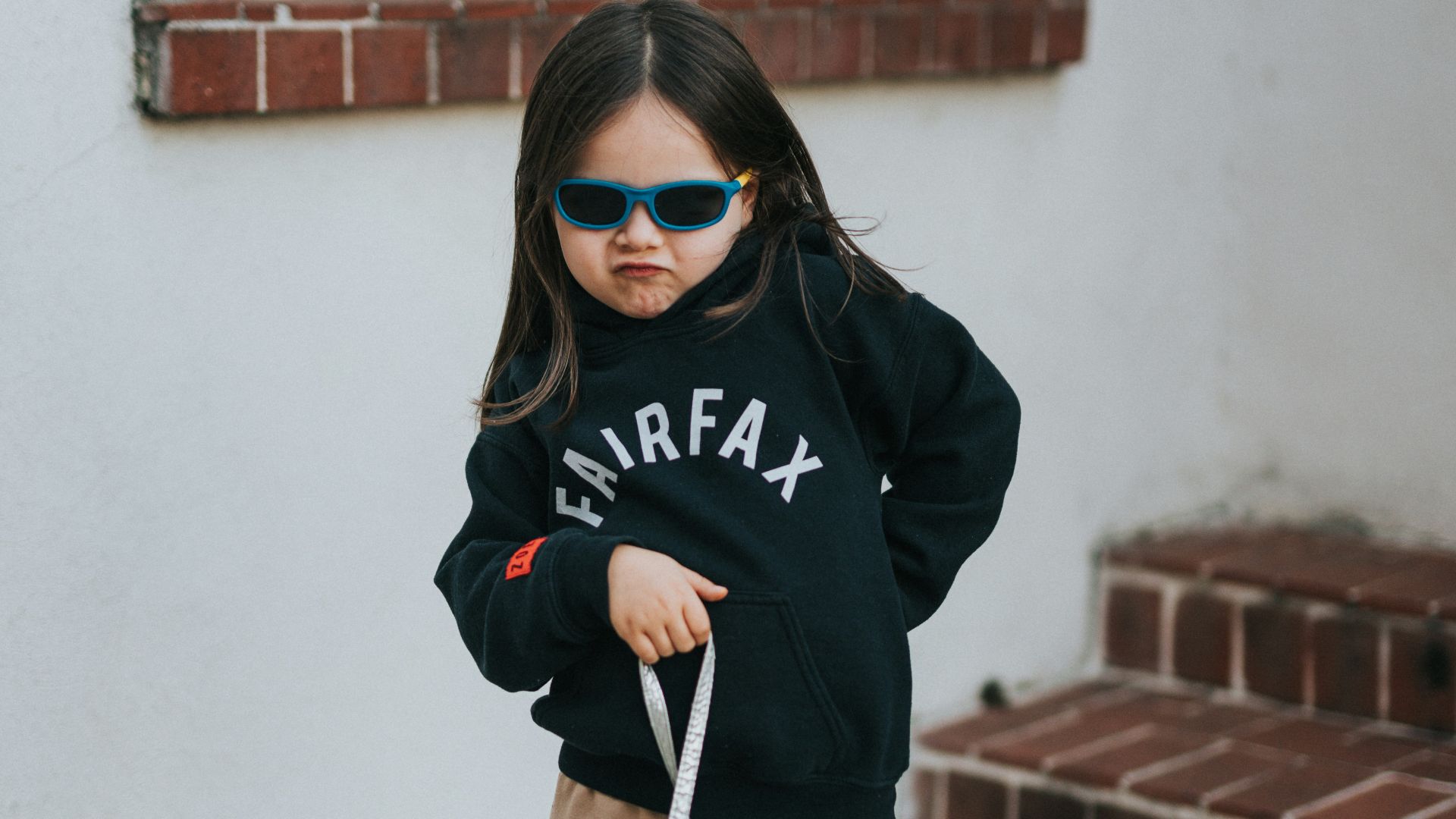 woman in black hoodie holding white short coated dog