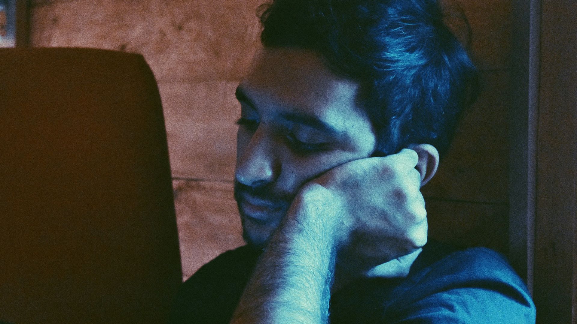 man leaning his face on his left hand