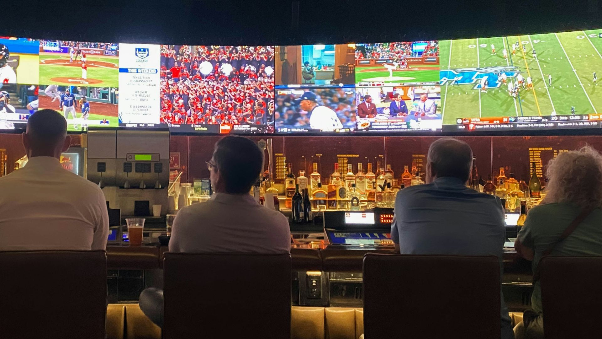a group of people sitting at a bar watching tv