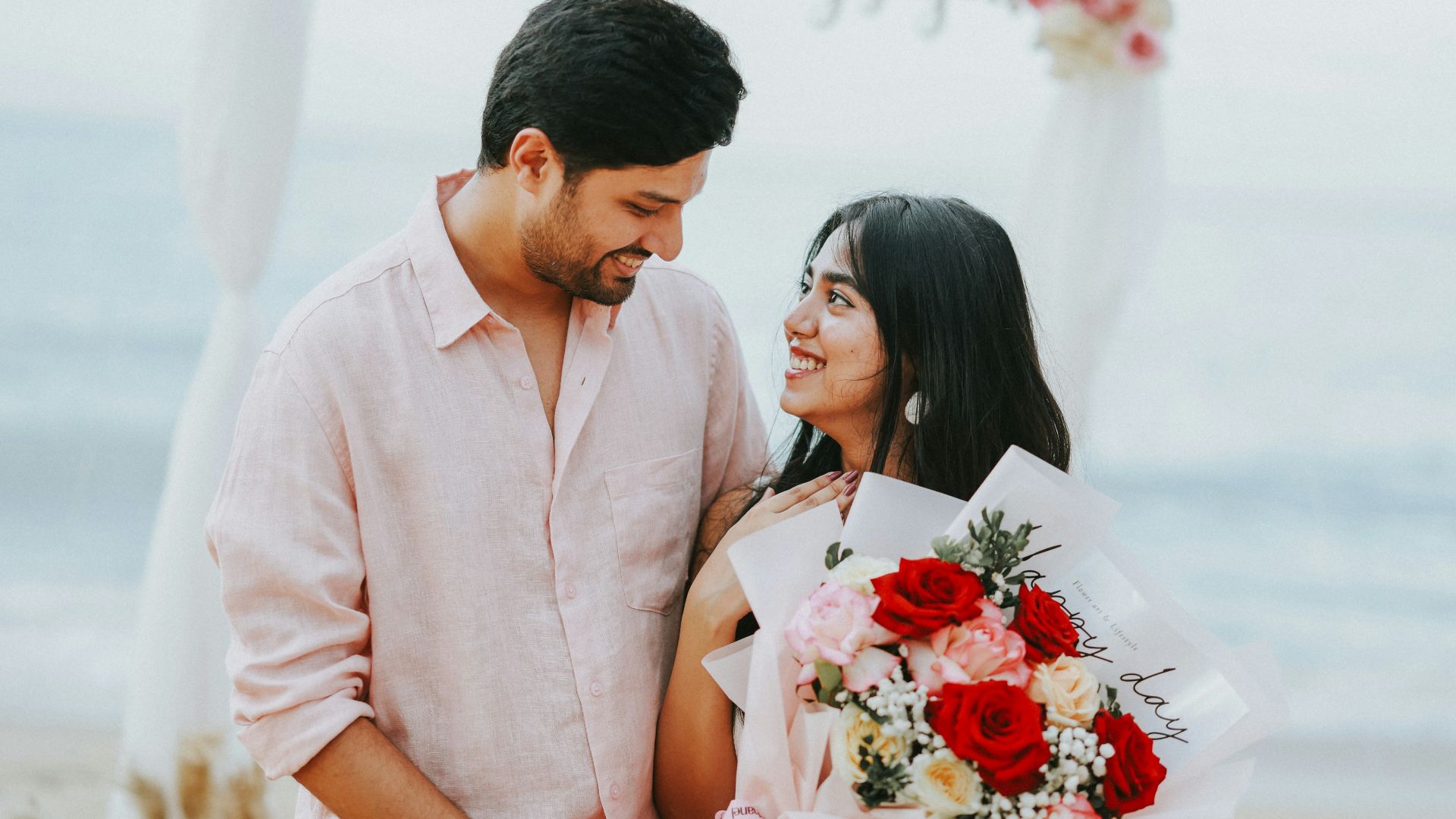 Couple on beach with flowers, wedding arch
