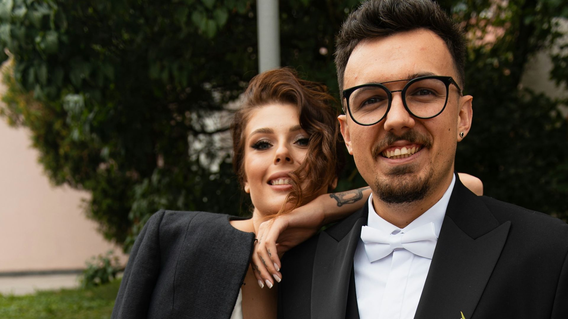 a man in a tuxedo and a woman in a white dress pose for