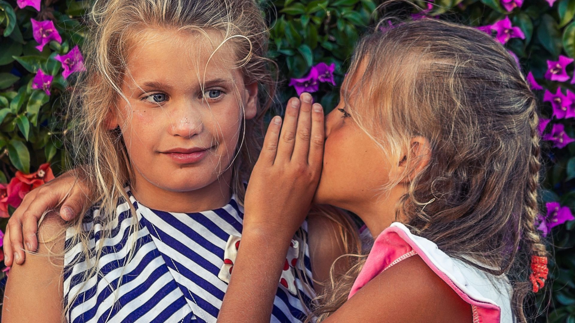 girl in white shirt kissing girl in blue and white stripe shirt