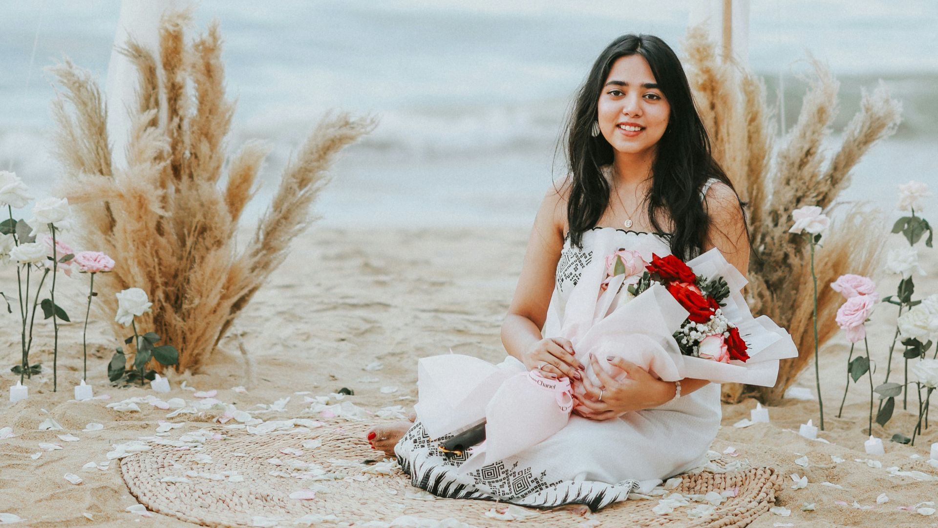 A woman with flowers on a beach wedding setup.
