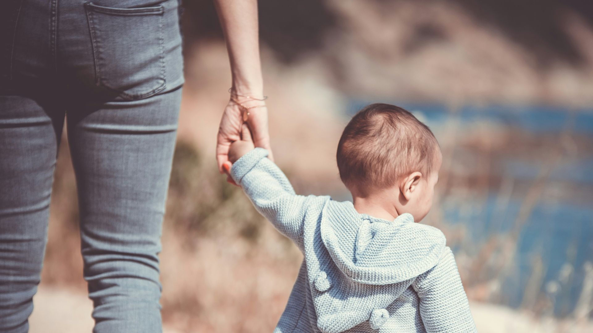 toddler's walking on the seashore with adult