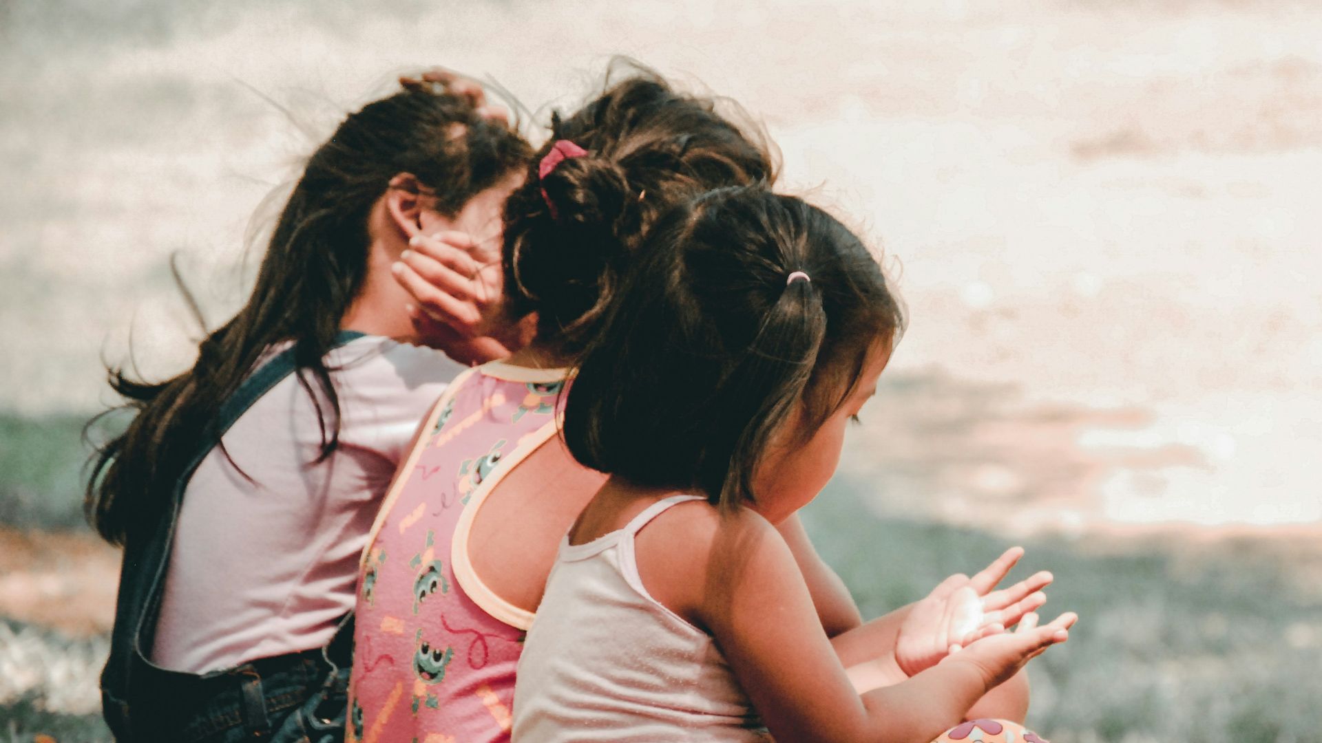 three children sitting on grass