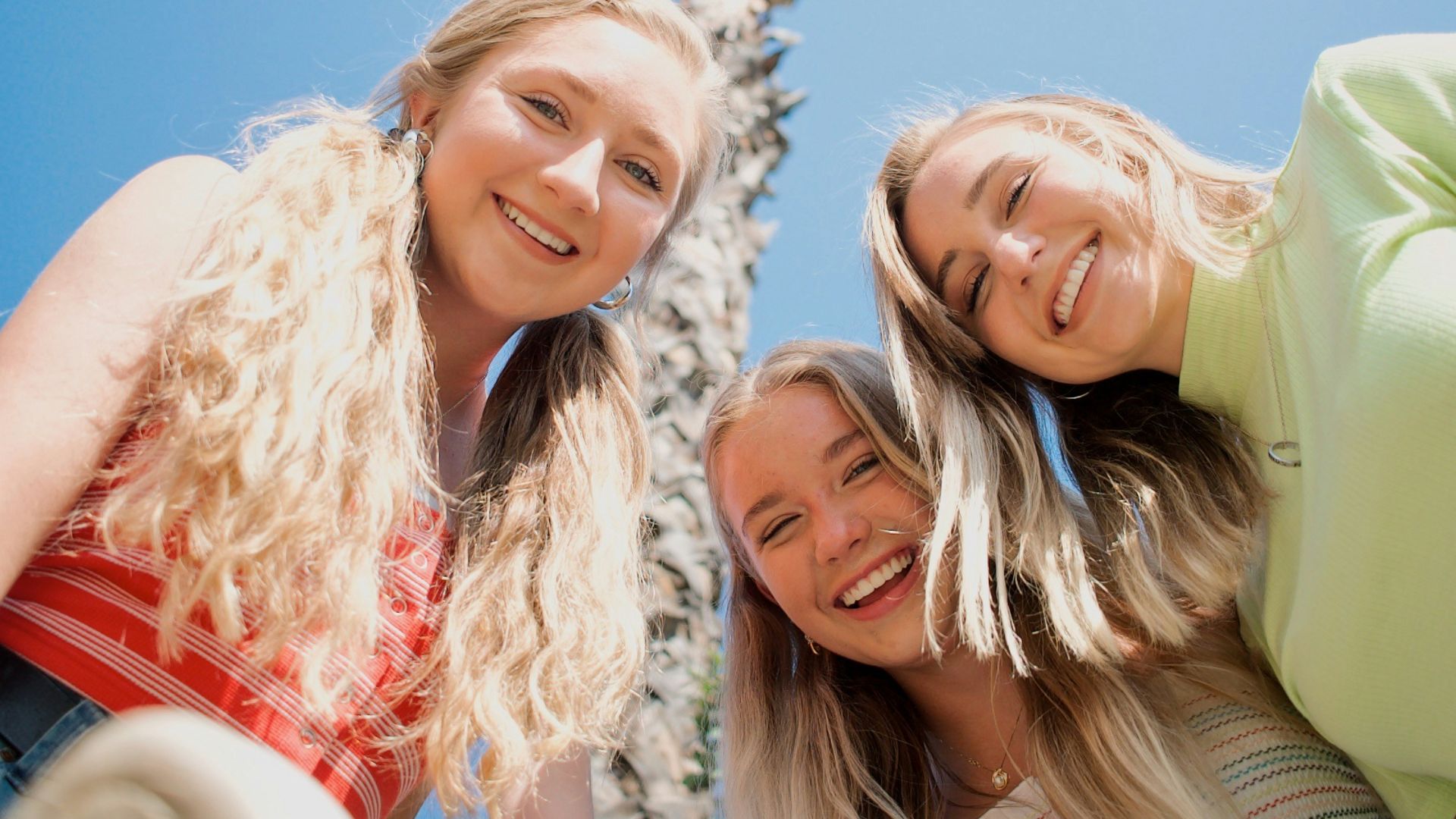 3 women smiling and standing under blue sky during daytime