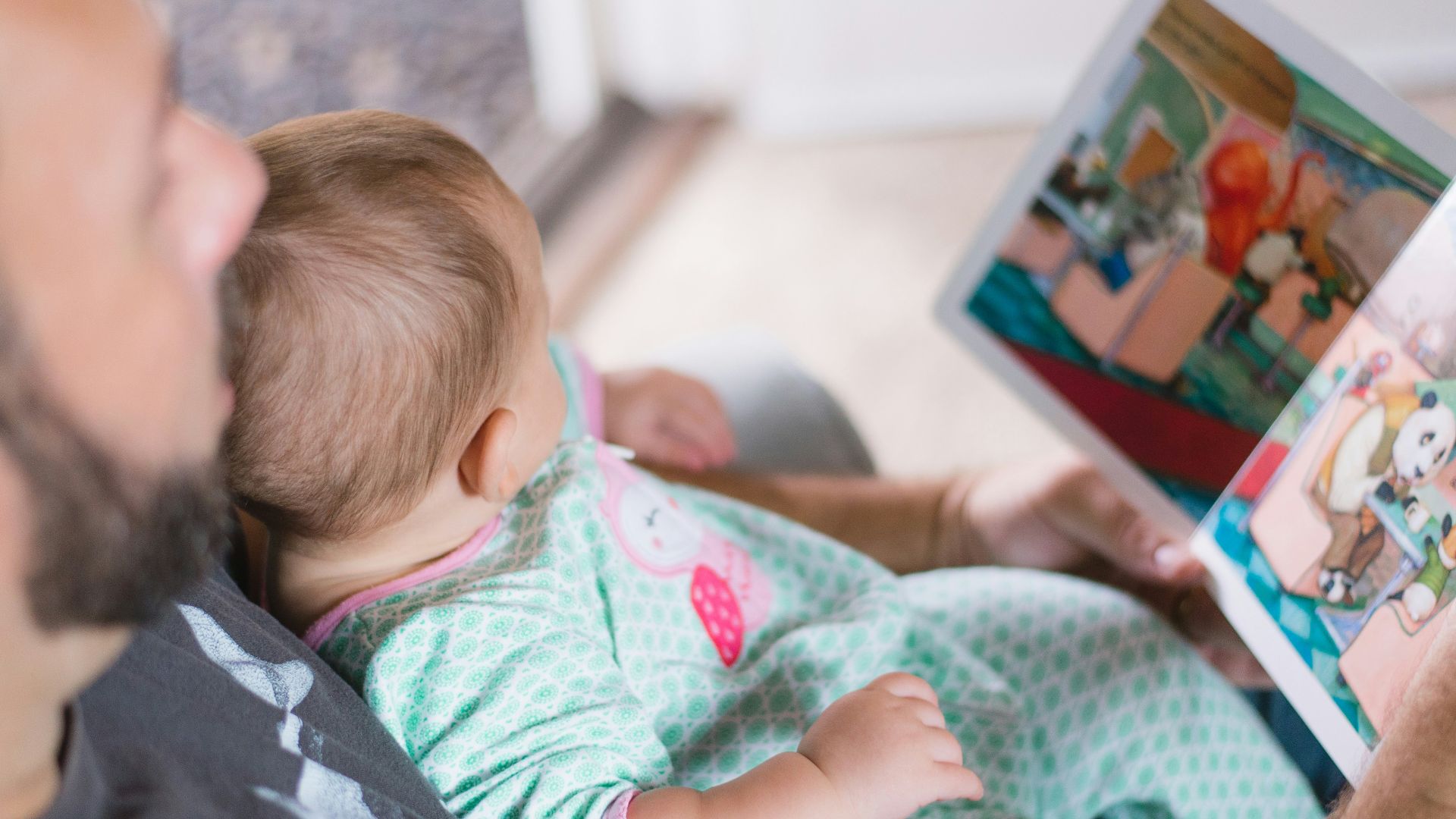 person carrying baby while reading book