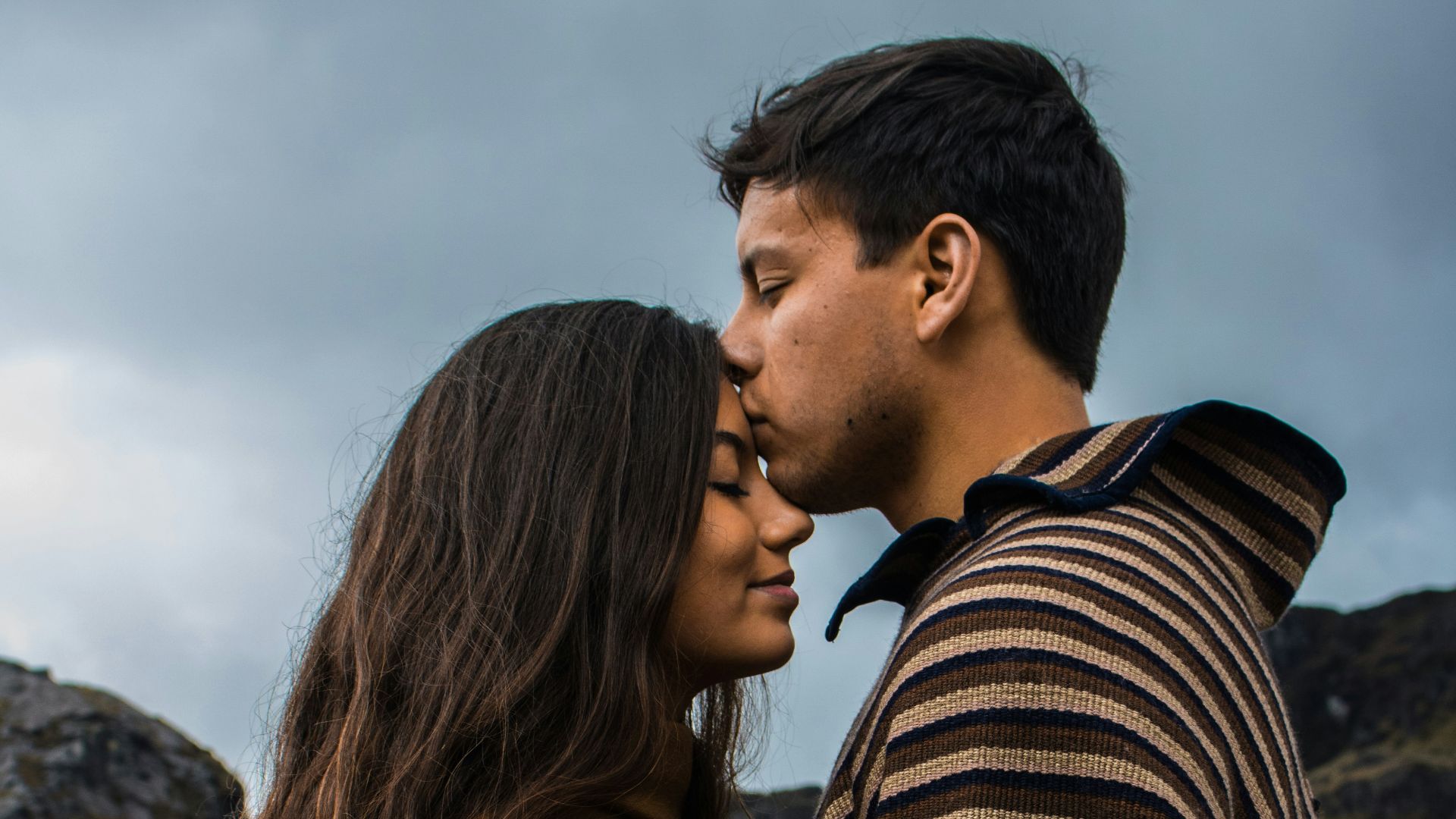 man kissing woman on forehead