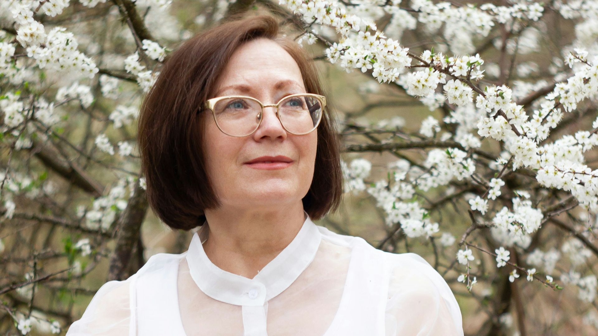 a woman standing in front of a flowering tree