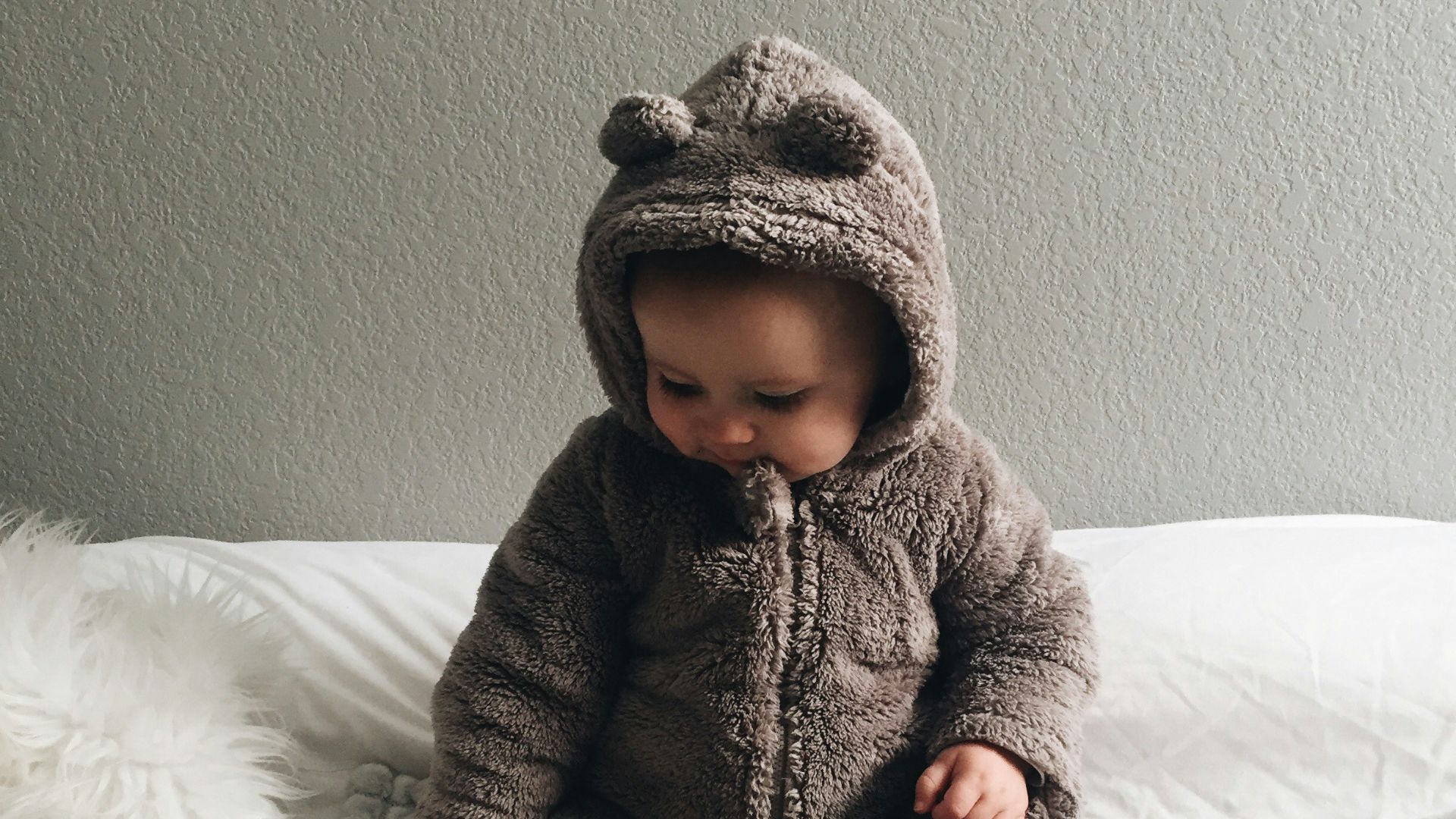 baby seating on white textile