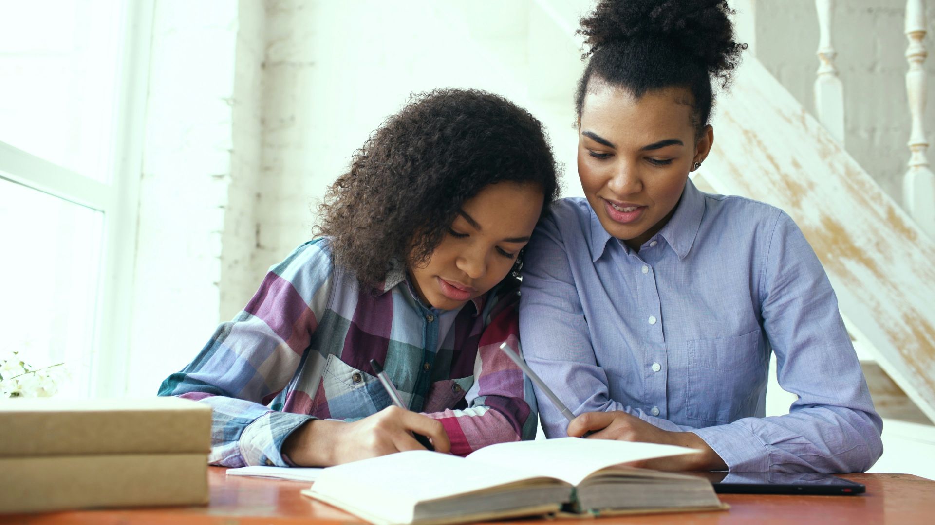Mother and daughter studying together at a table.