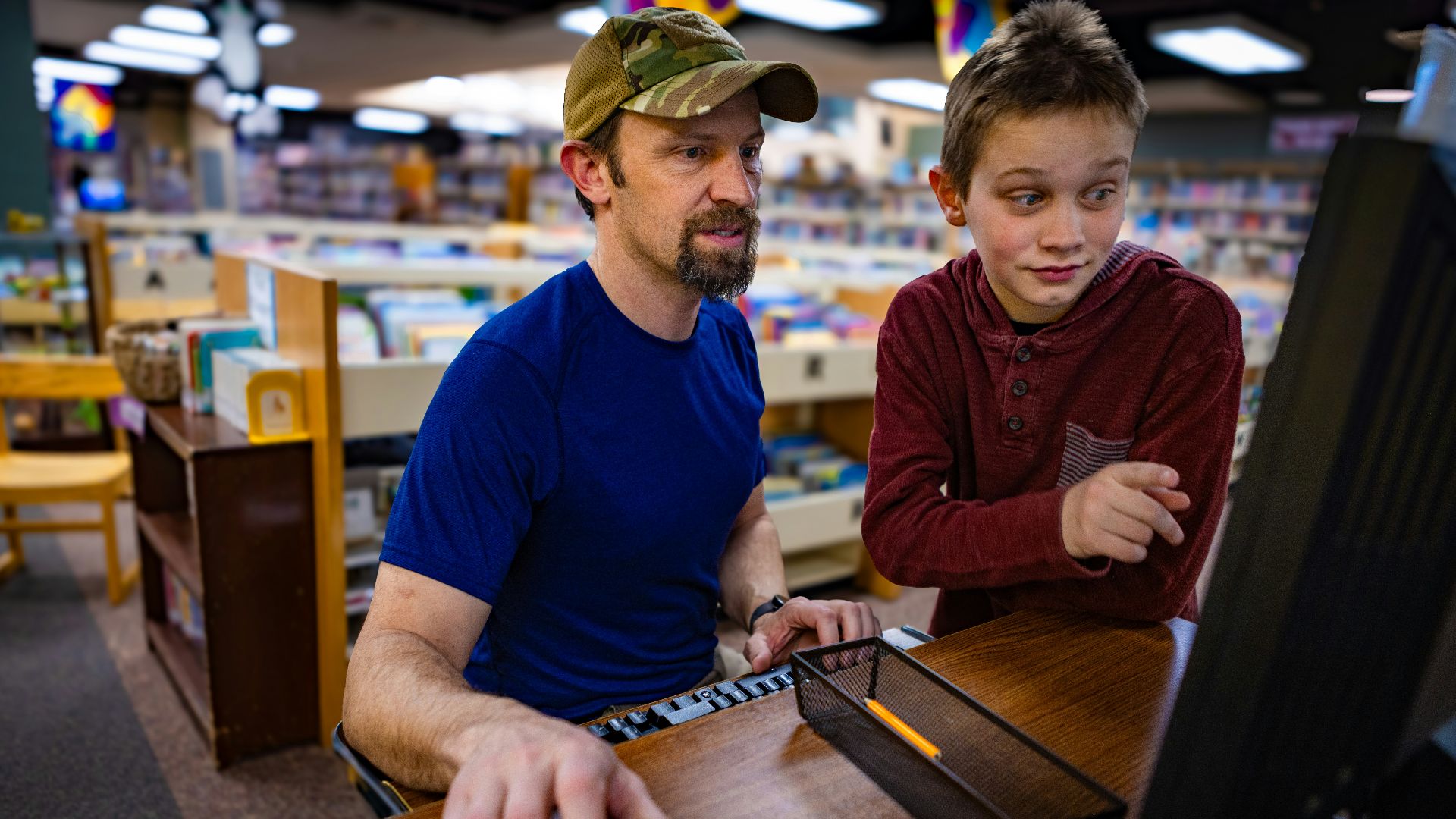 A man and boy work on a computer.