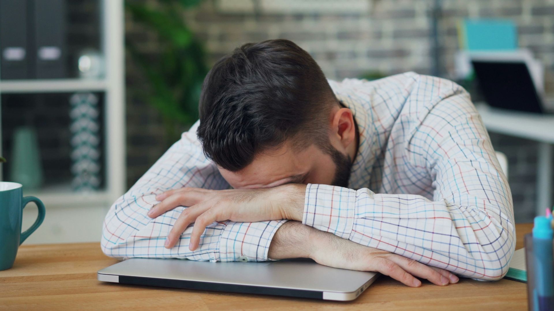 a man sitting at a desk with his head in his hands