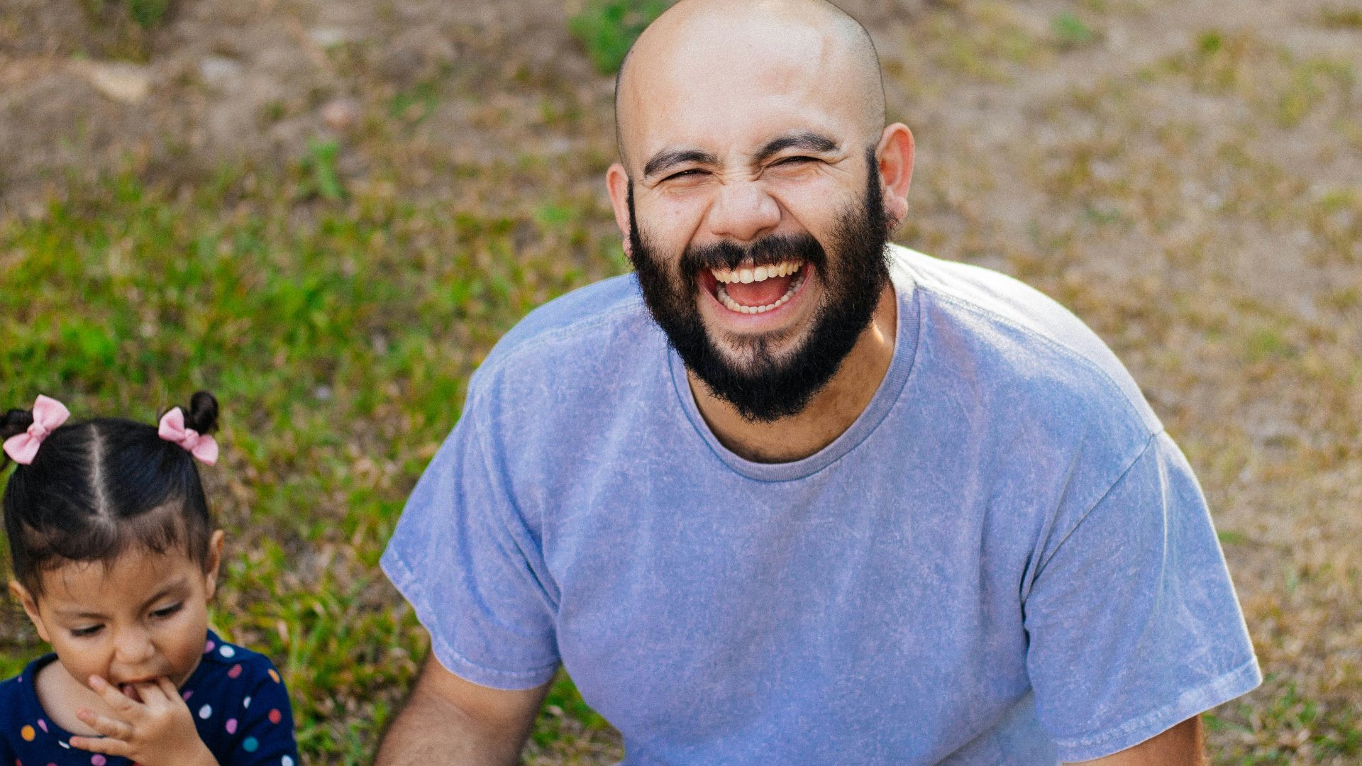 a man and a little girl sitting on the ground