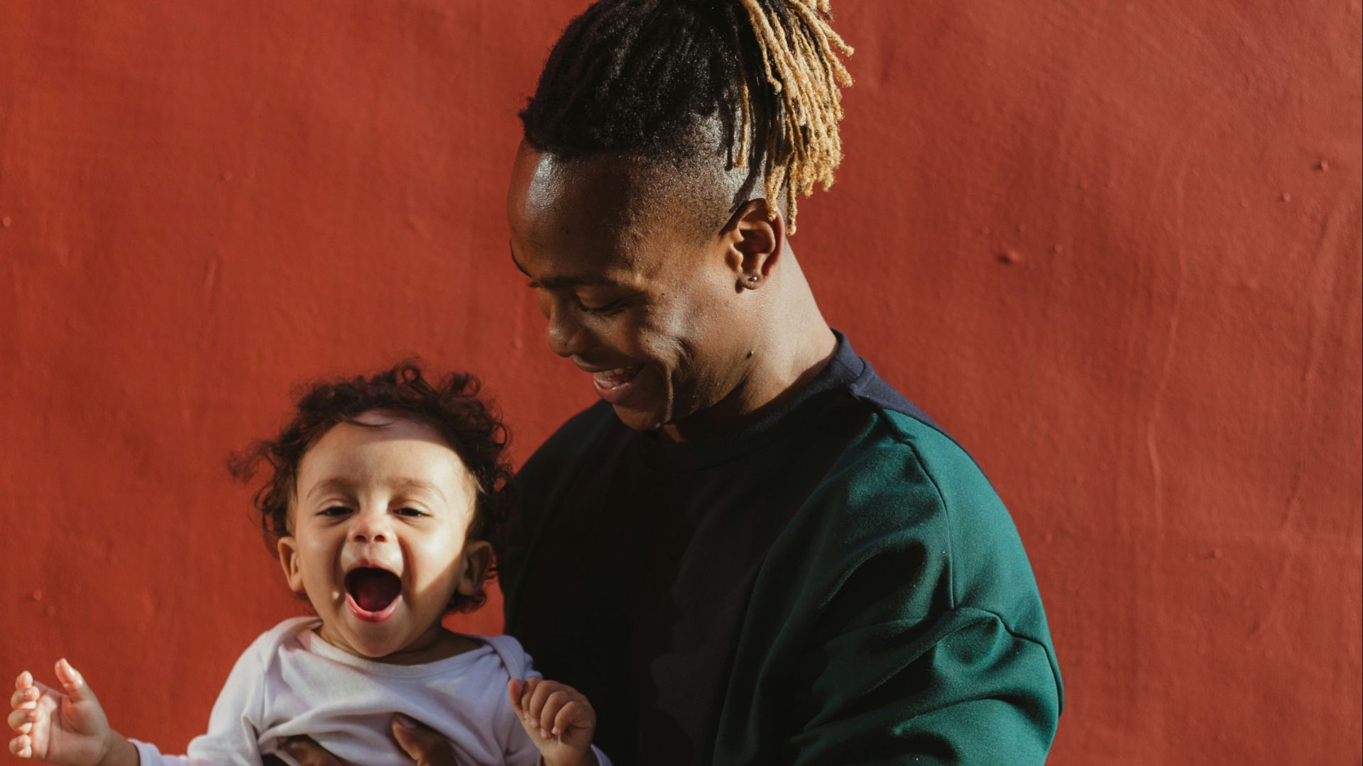 smiling man carrying child and playing