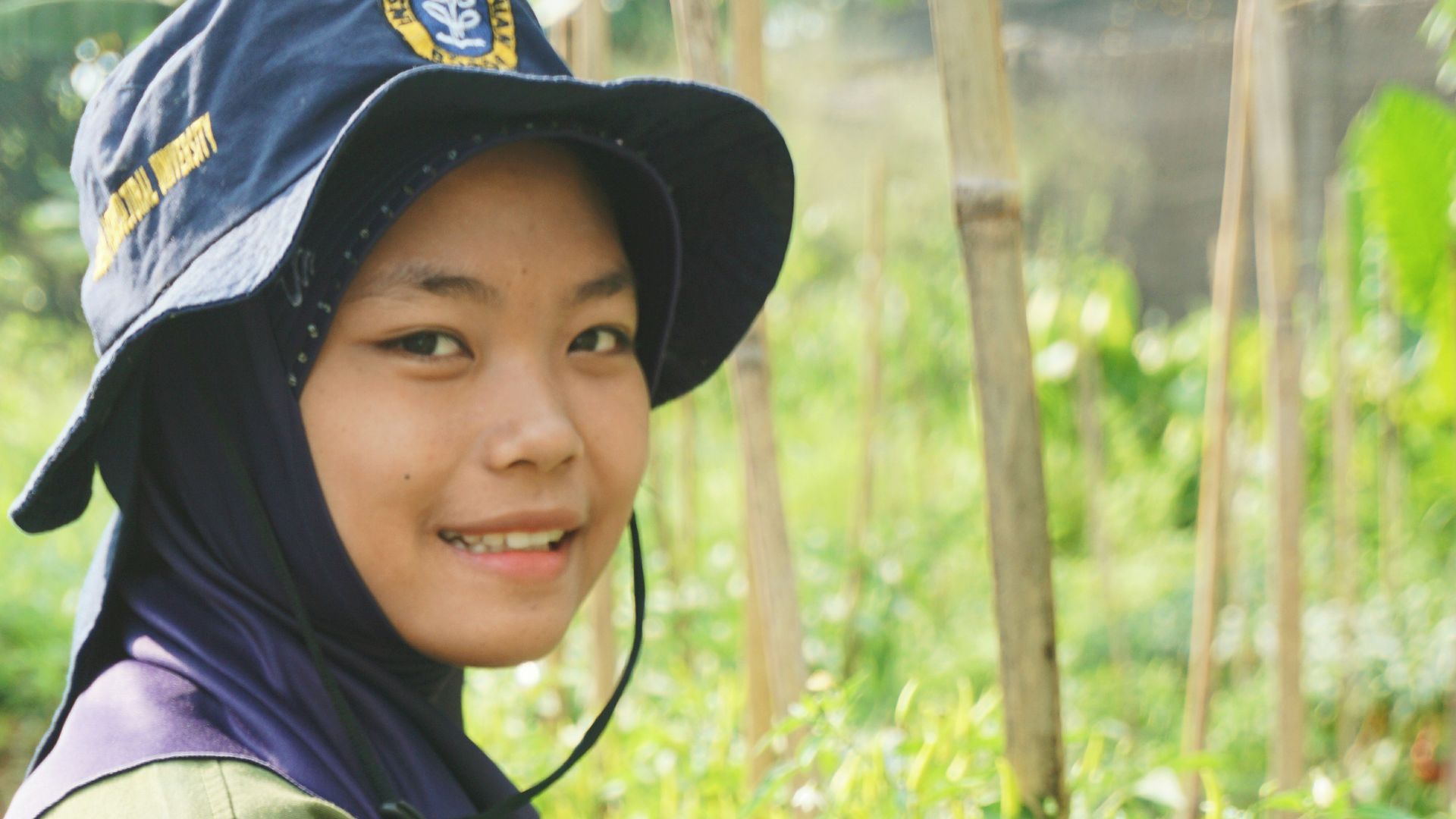 woman in green jacket and black hat holding green plant