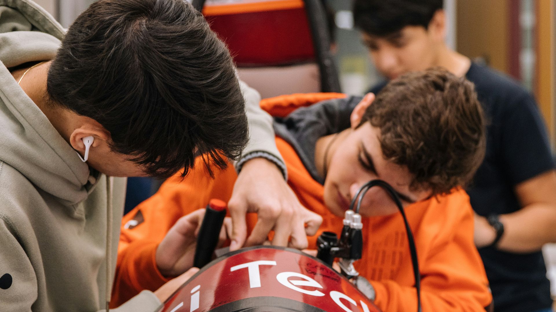 boy in orange shirt holding red and black backpack