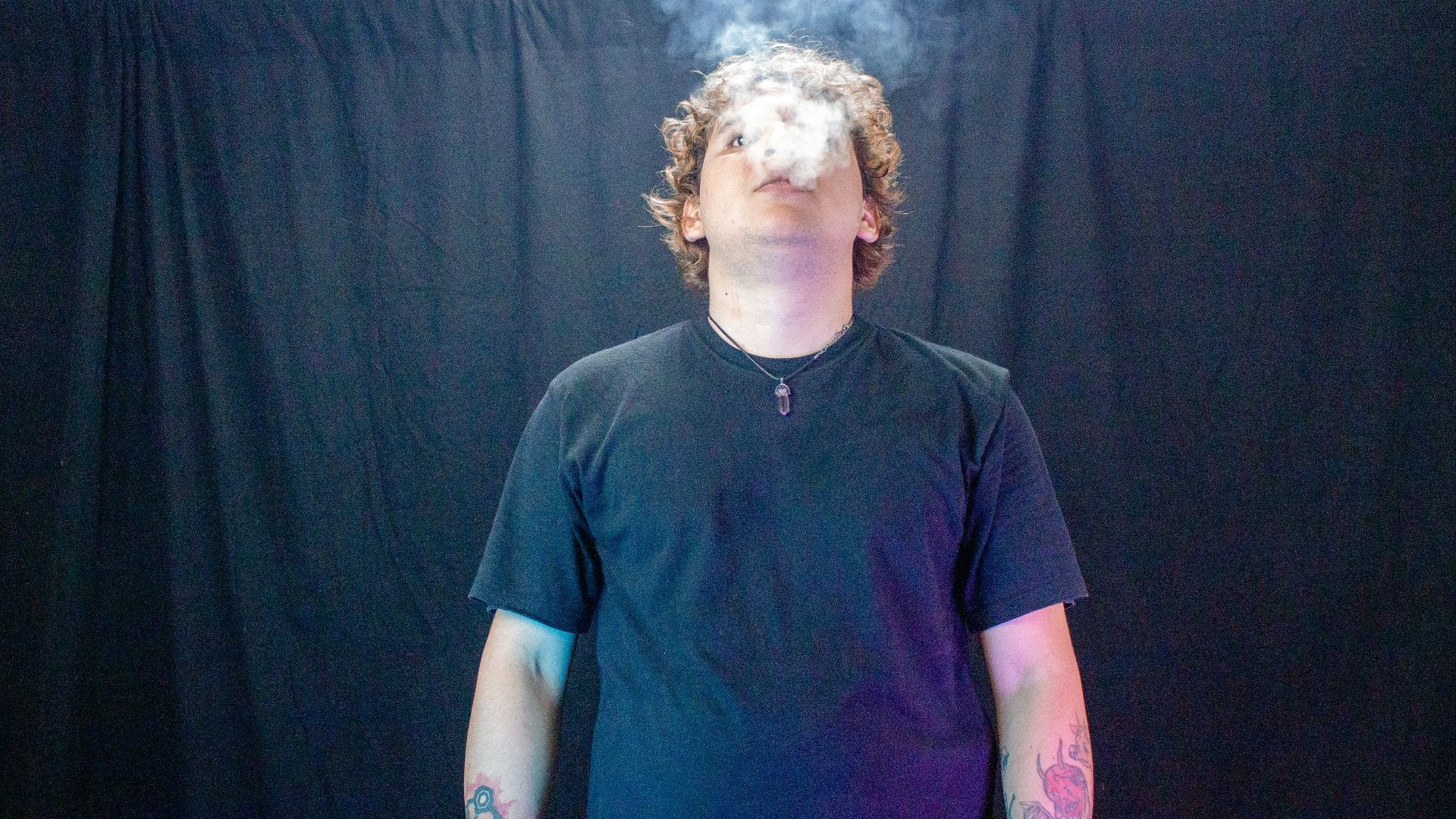 Man exhaling smoke against a dark background