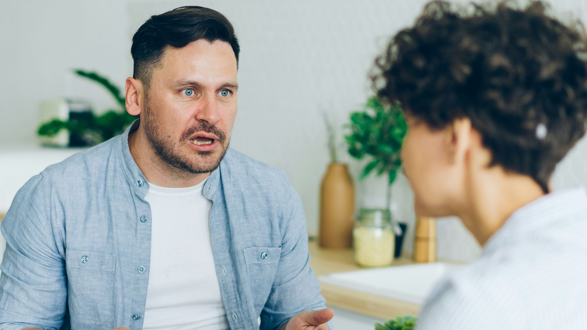 a man sitting at a table talking to a woman