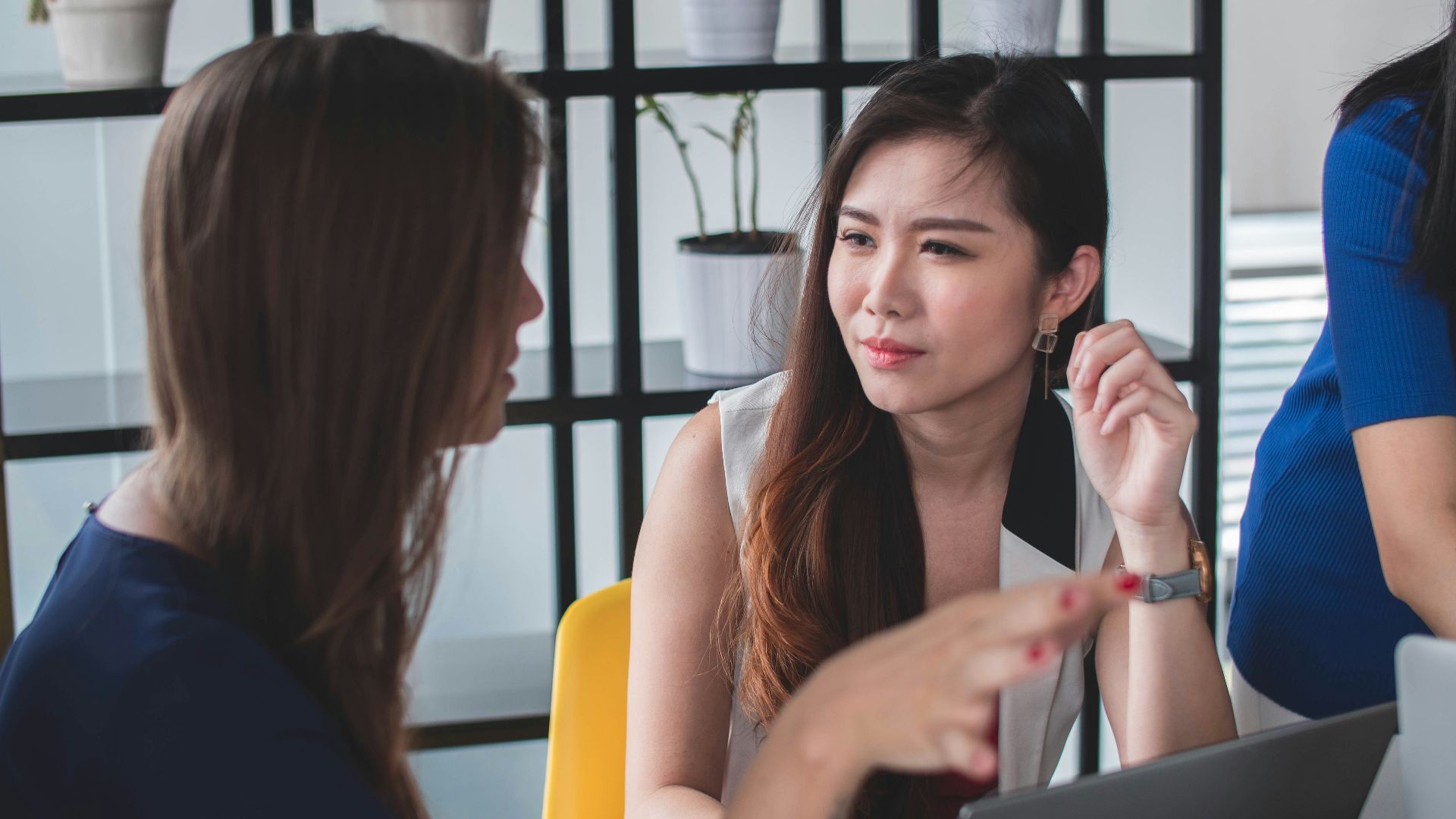 woman sitting on yellow armless chair near gray laptop computer