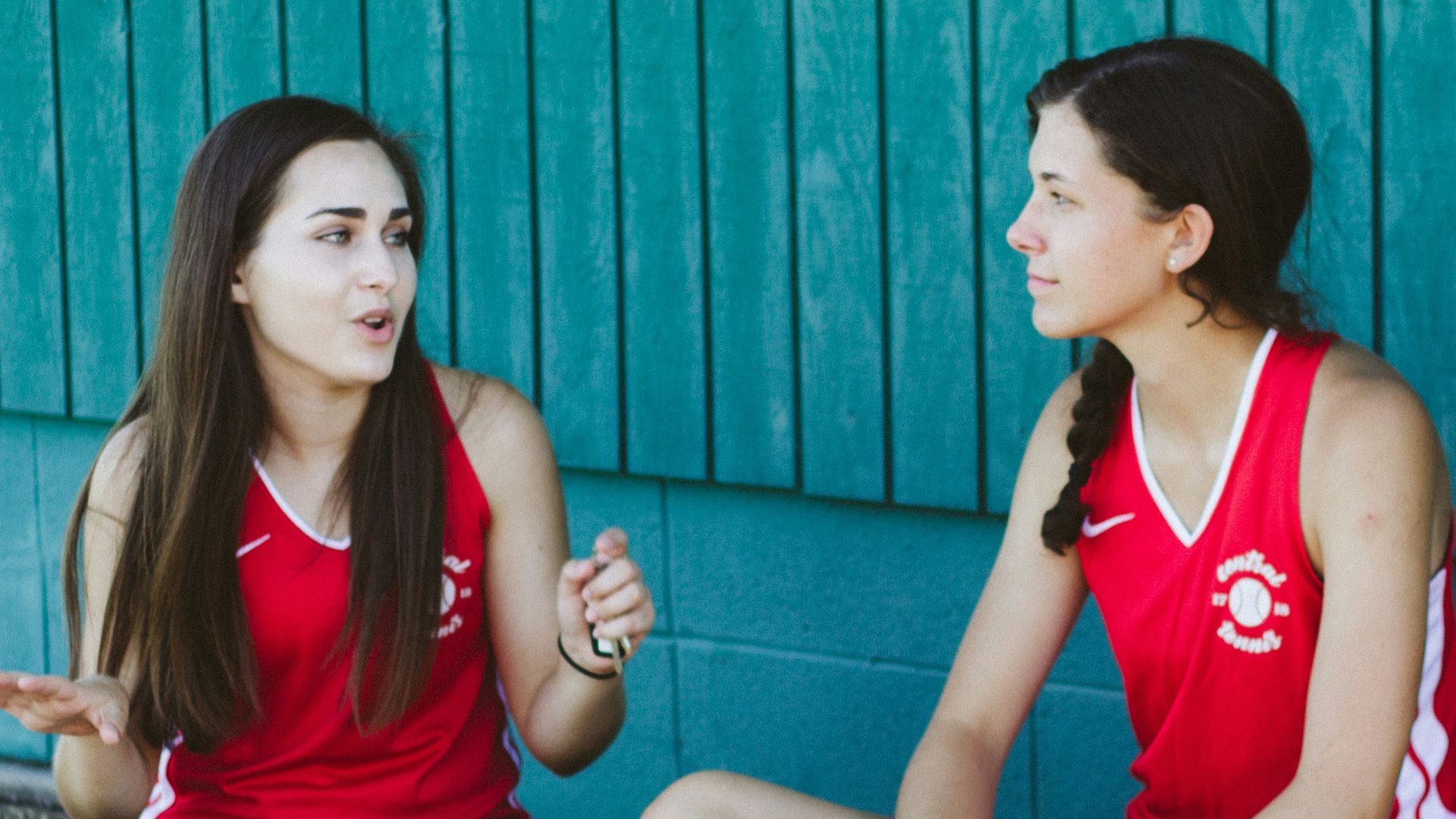 woman in red Nike tank top sitting beside woman in red tank top