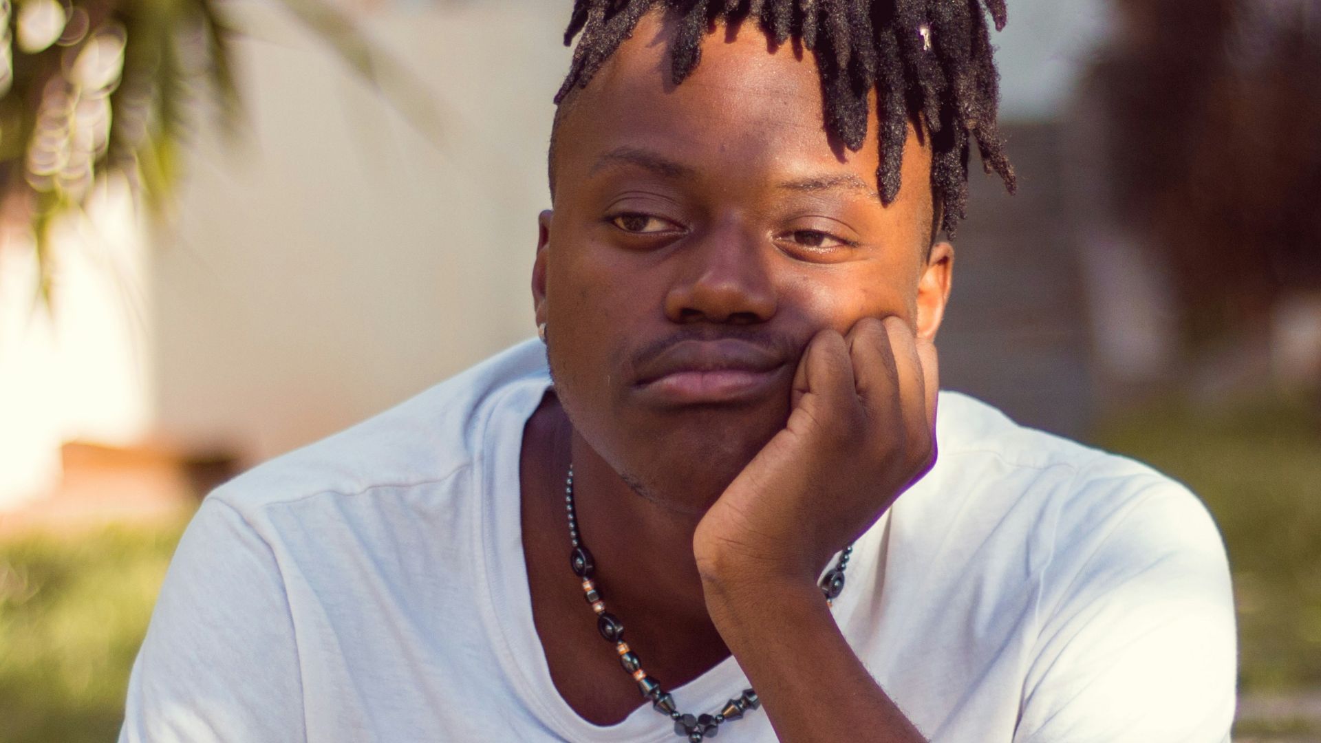 man in white crew neck t-shirt sitting on brown wooden chair