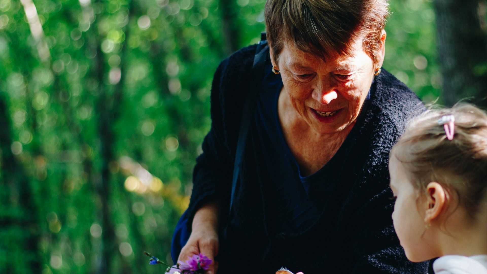 woman in black long sleeve shirt holding purple flower