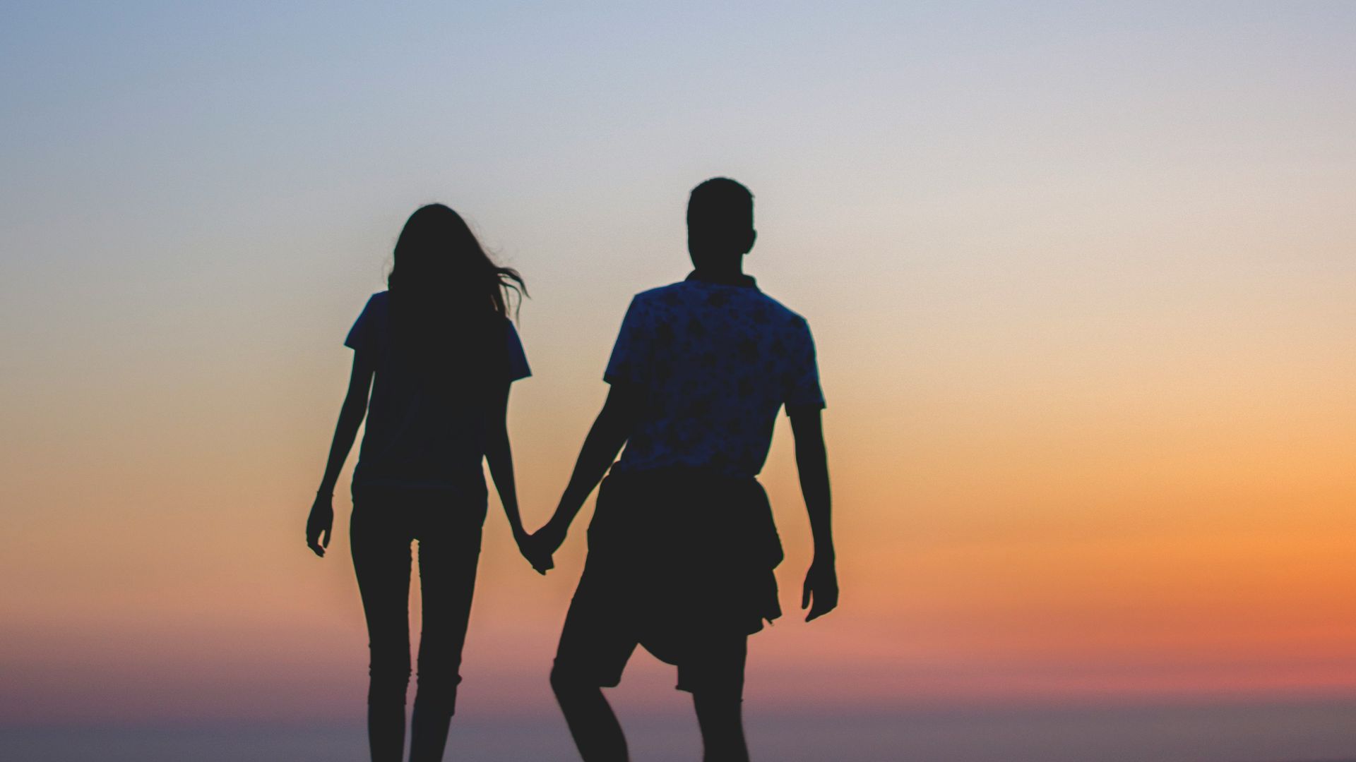 man and woman holding hands in silhouette photography