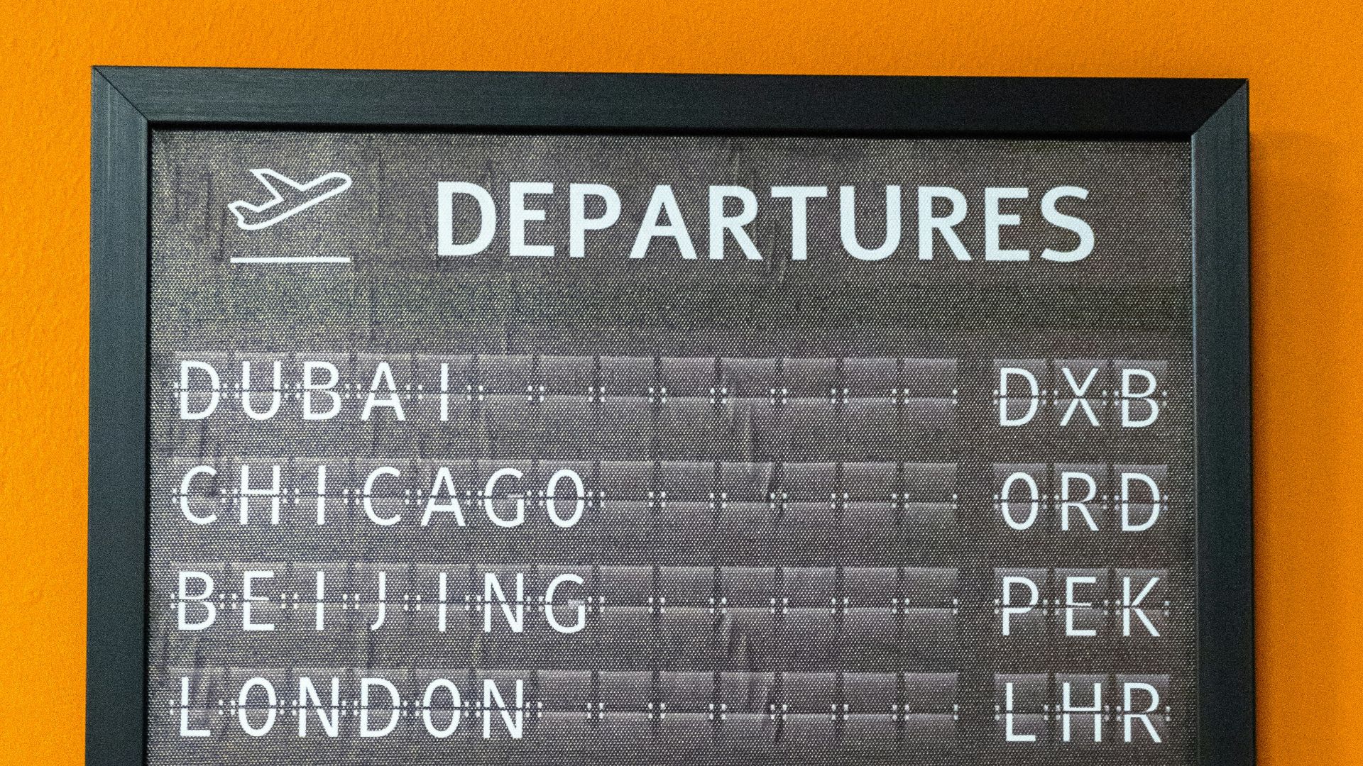 An airport departure board displays flight information.