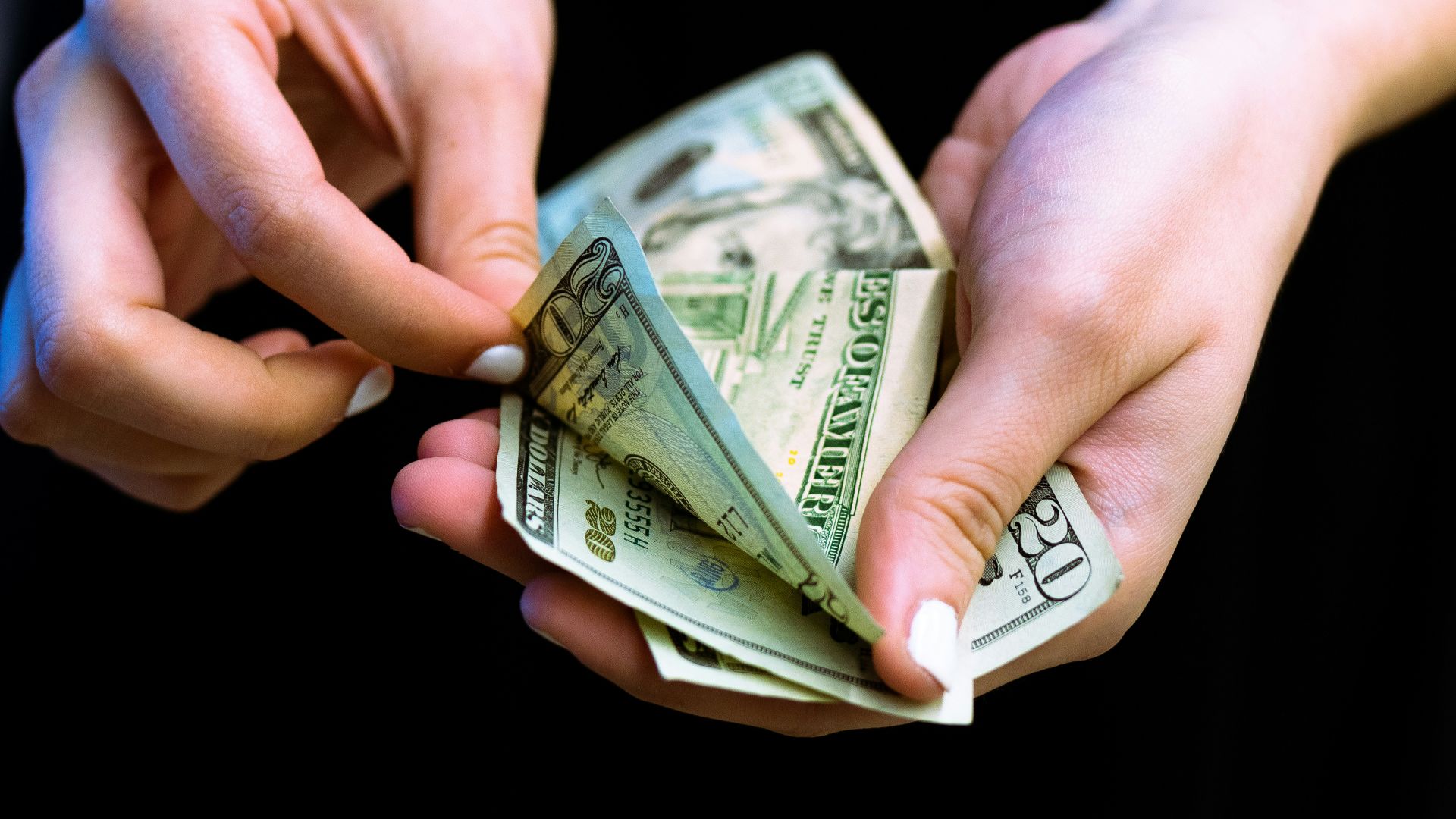 person holding fan of 100 us dollar bill