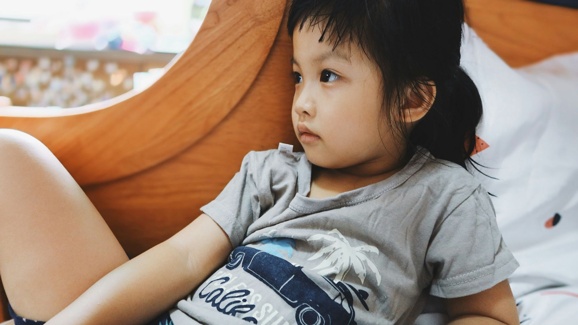boy in gray crew neck t-shirt lying on bed