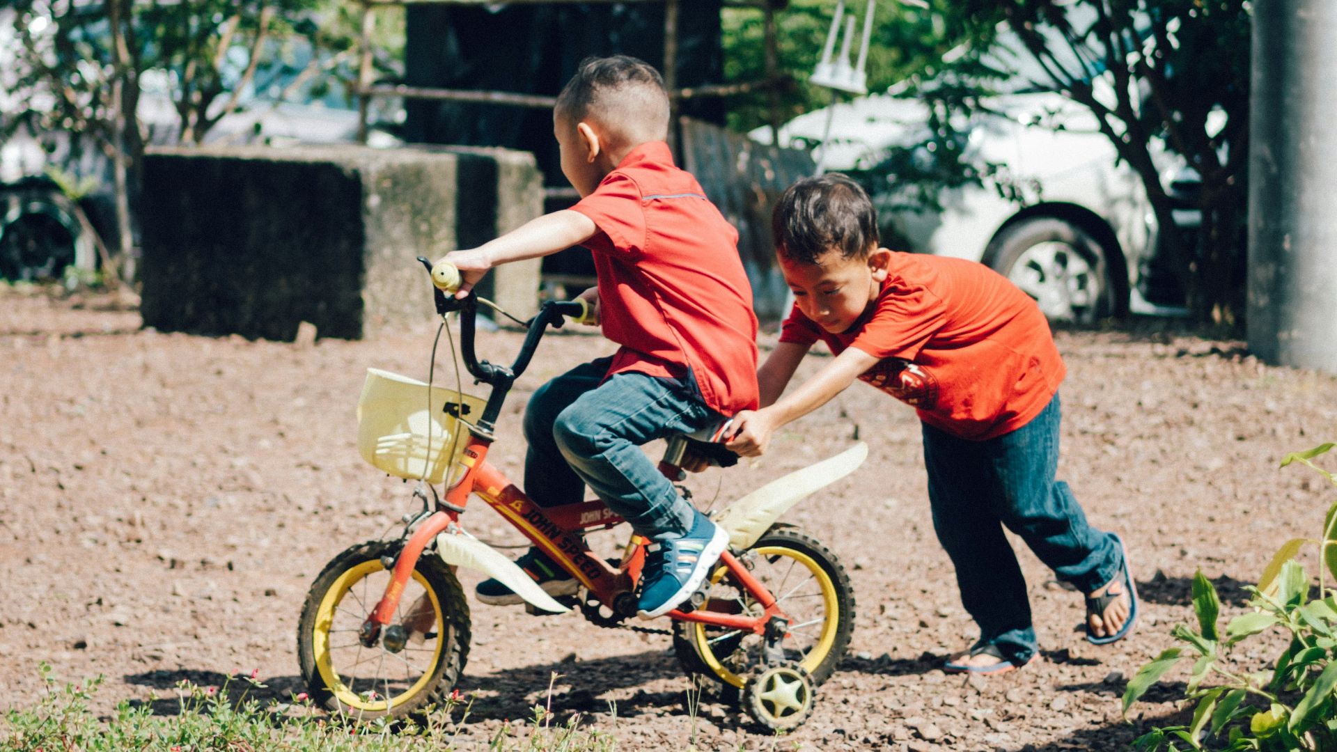 boy in orange t-shirt riding on bicycle during daytime