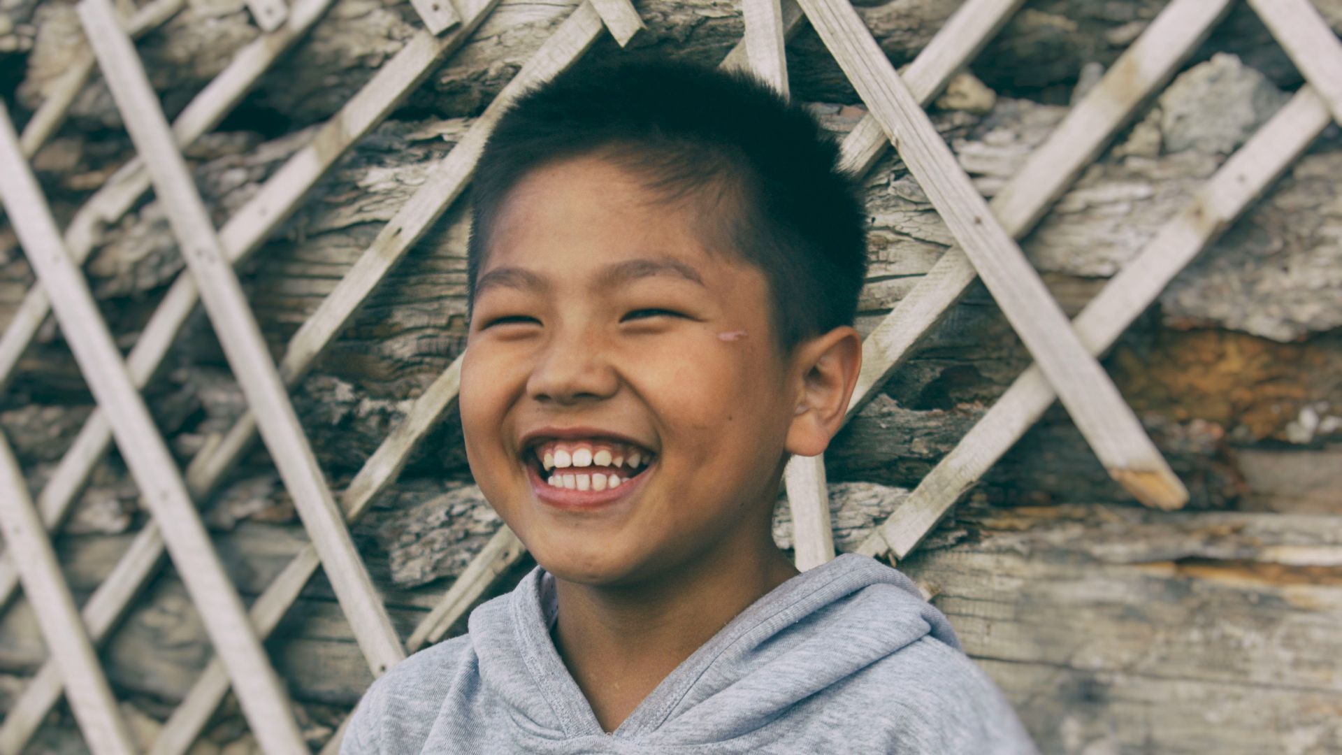 smiling boy in gray and blue hoodie