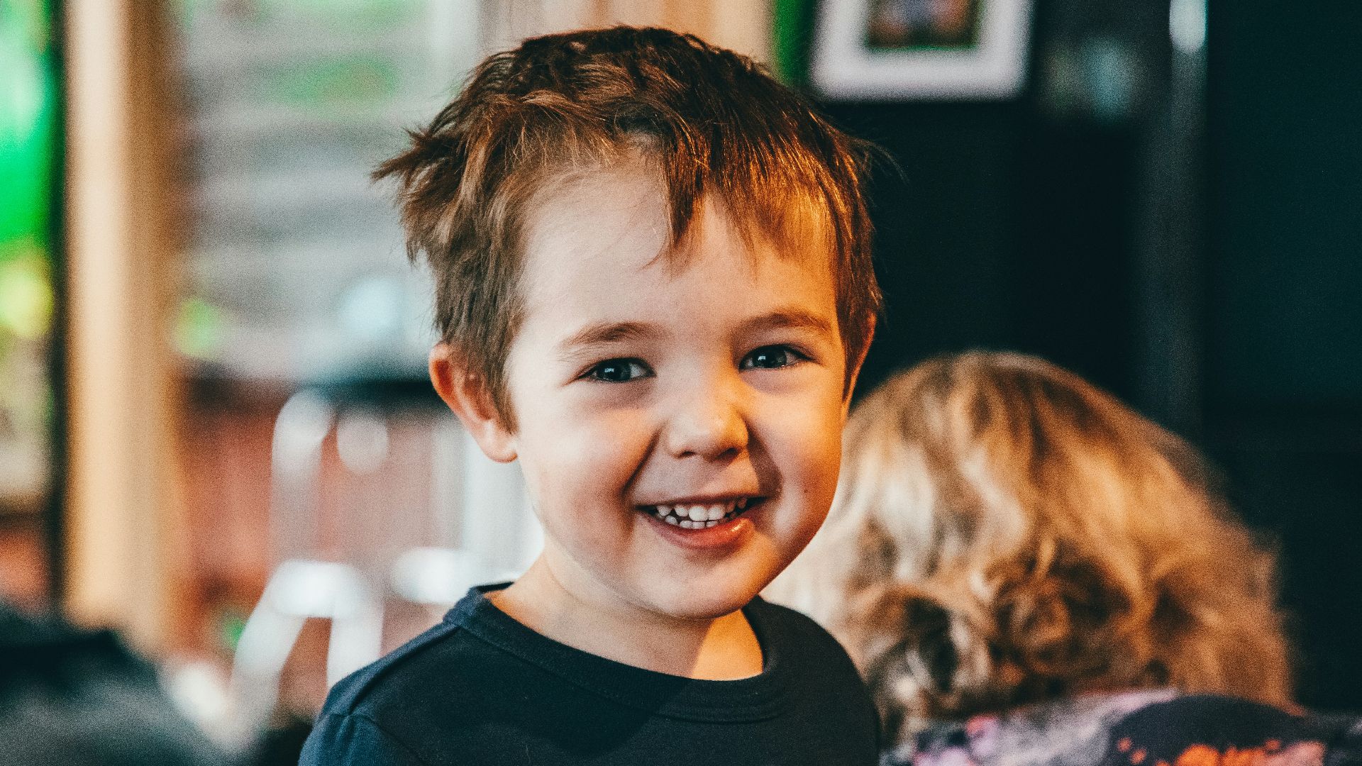 a young boy smiling at the camera in a restaurant