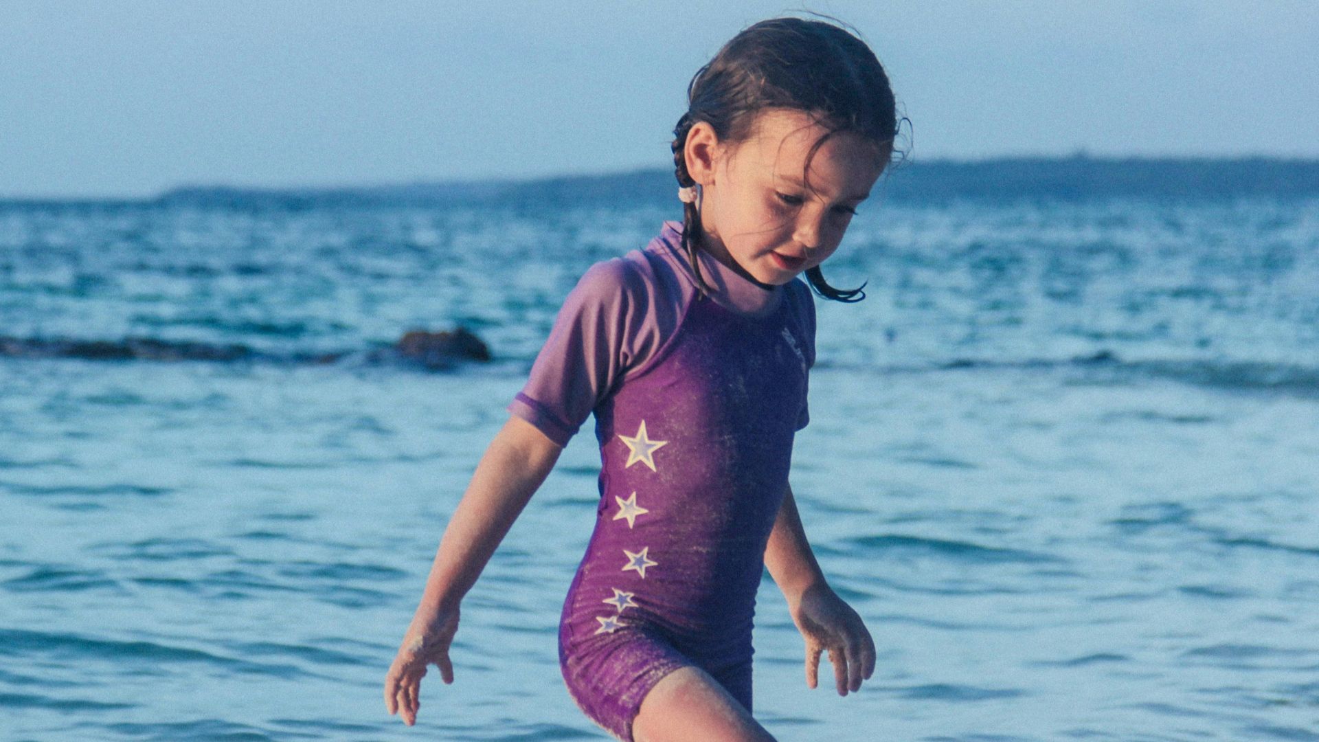 girl in purple swim wear standing near shore