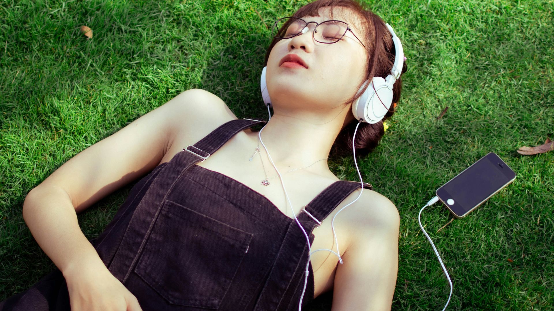 a woman laying on the grass listening to music