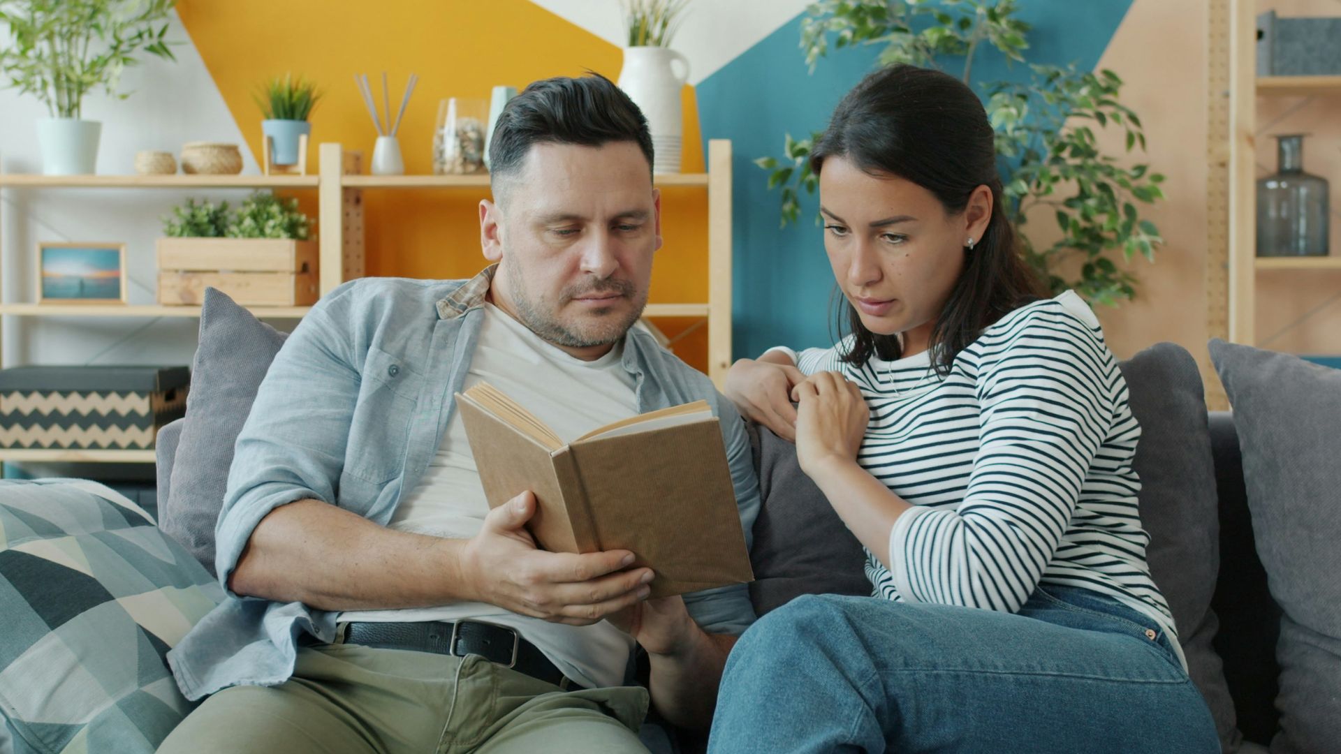 Couple sitting on couch looking at a box