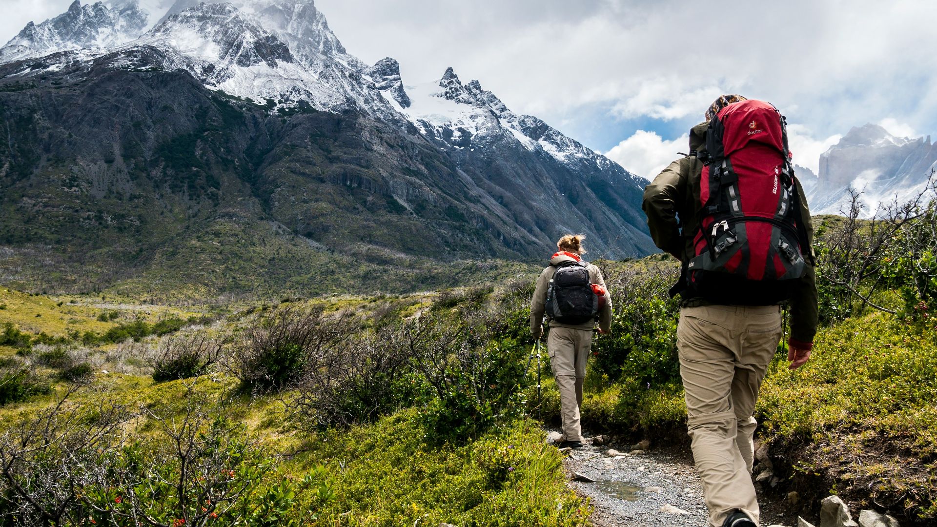 two person walking towards mountain covered with snow