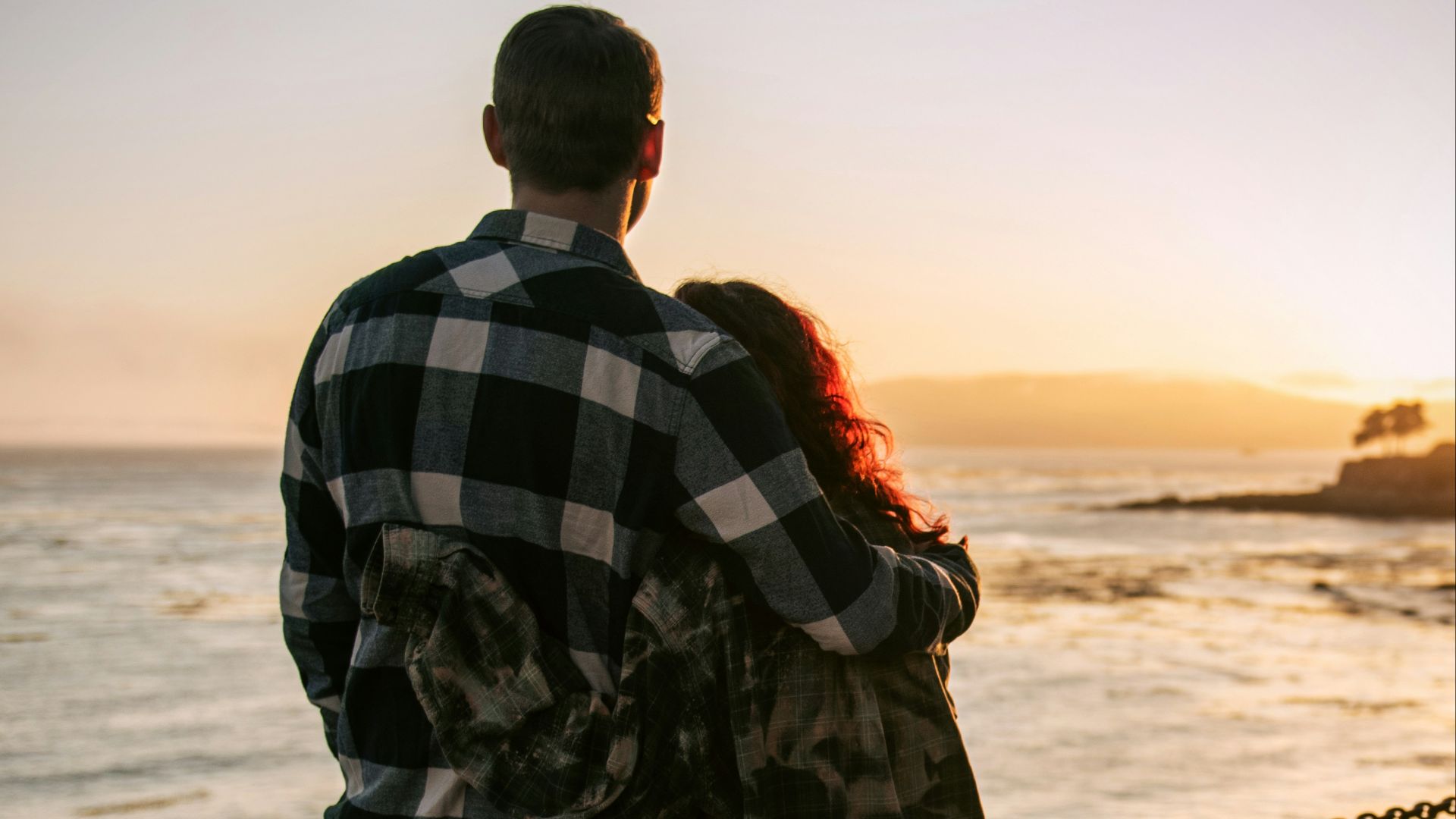 a man and woman kissing on a beach