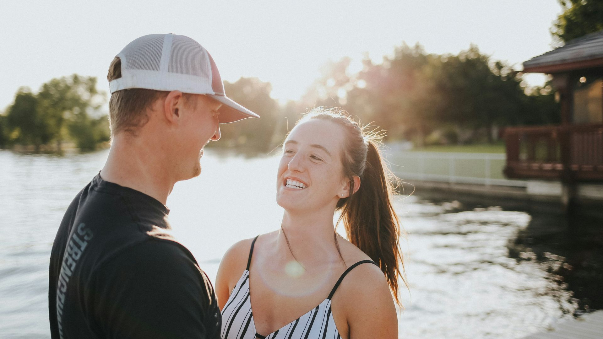 woman in white and black bikini top and white hat standing beside man in black shirt
