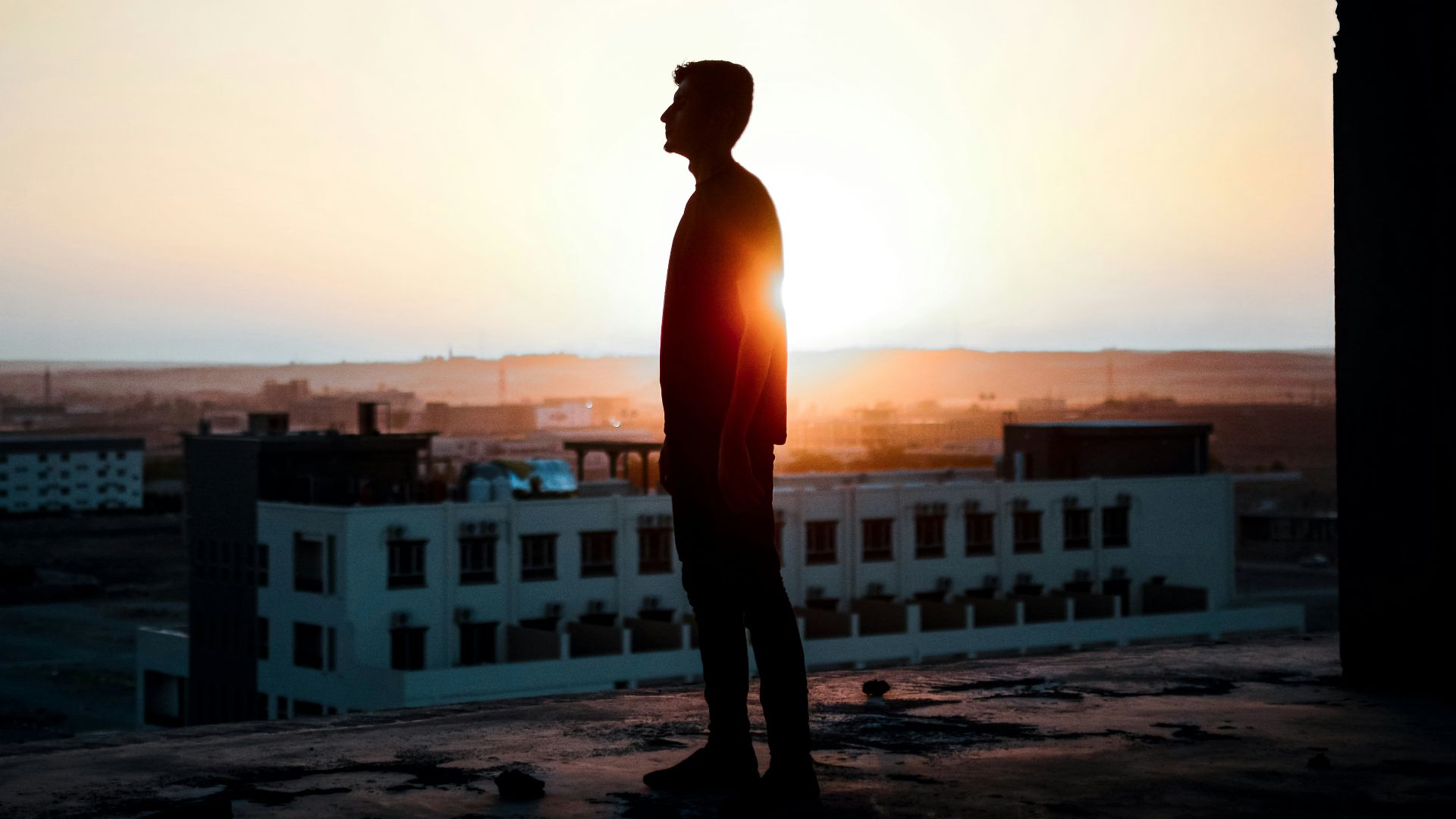 a man standing on top of a roof next to a building