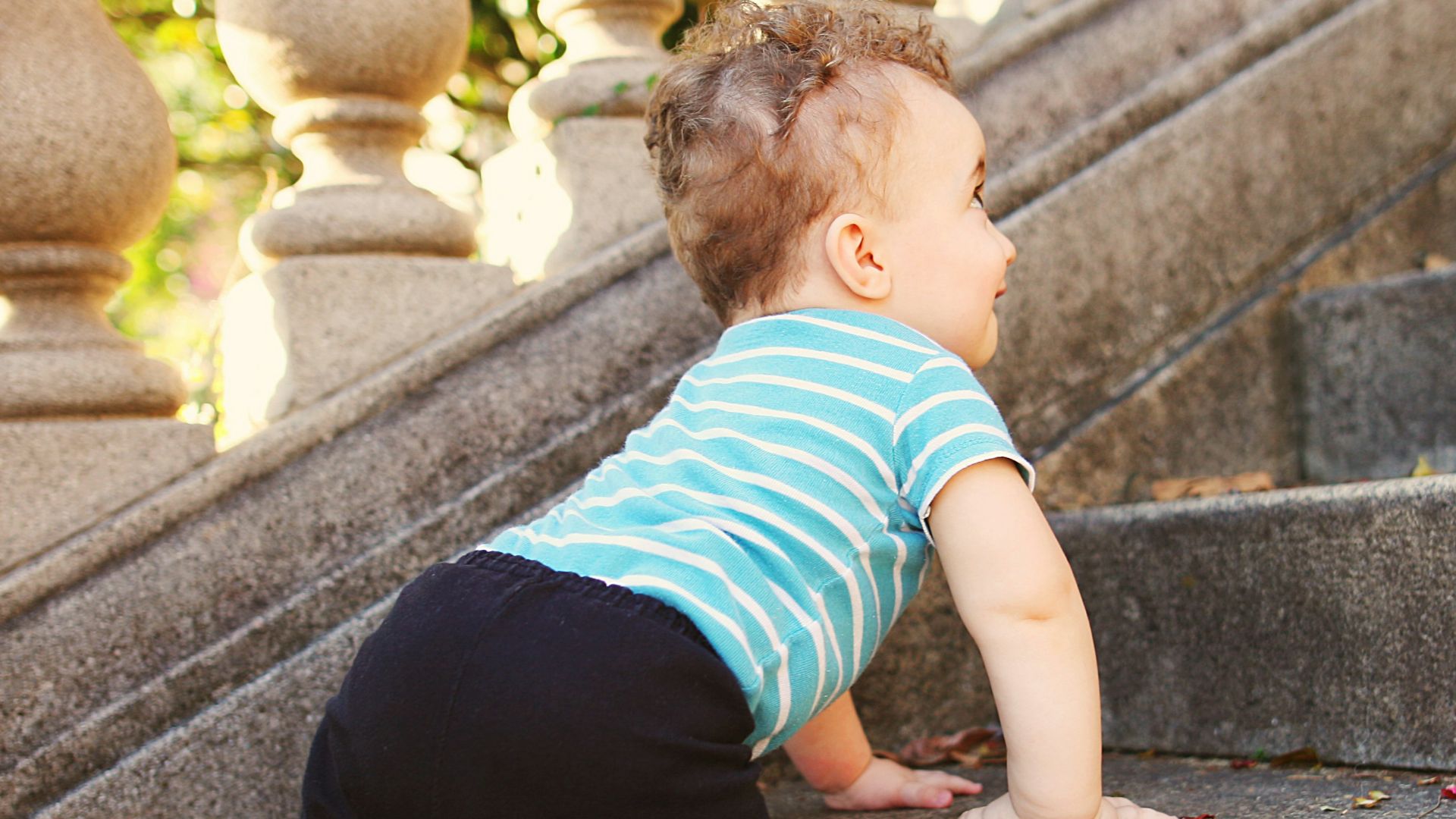 boy in green and white striped t-shirt and black pants sitting on concrete stairs during