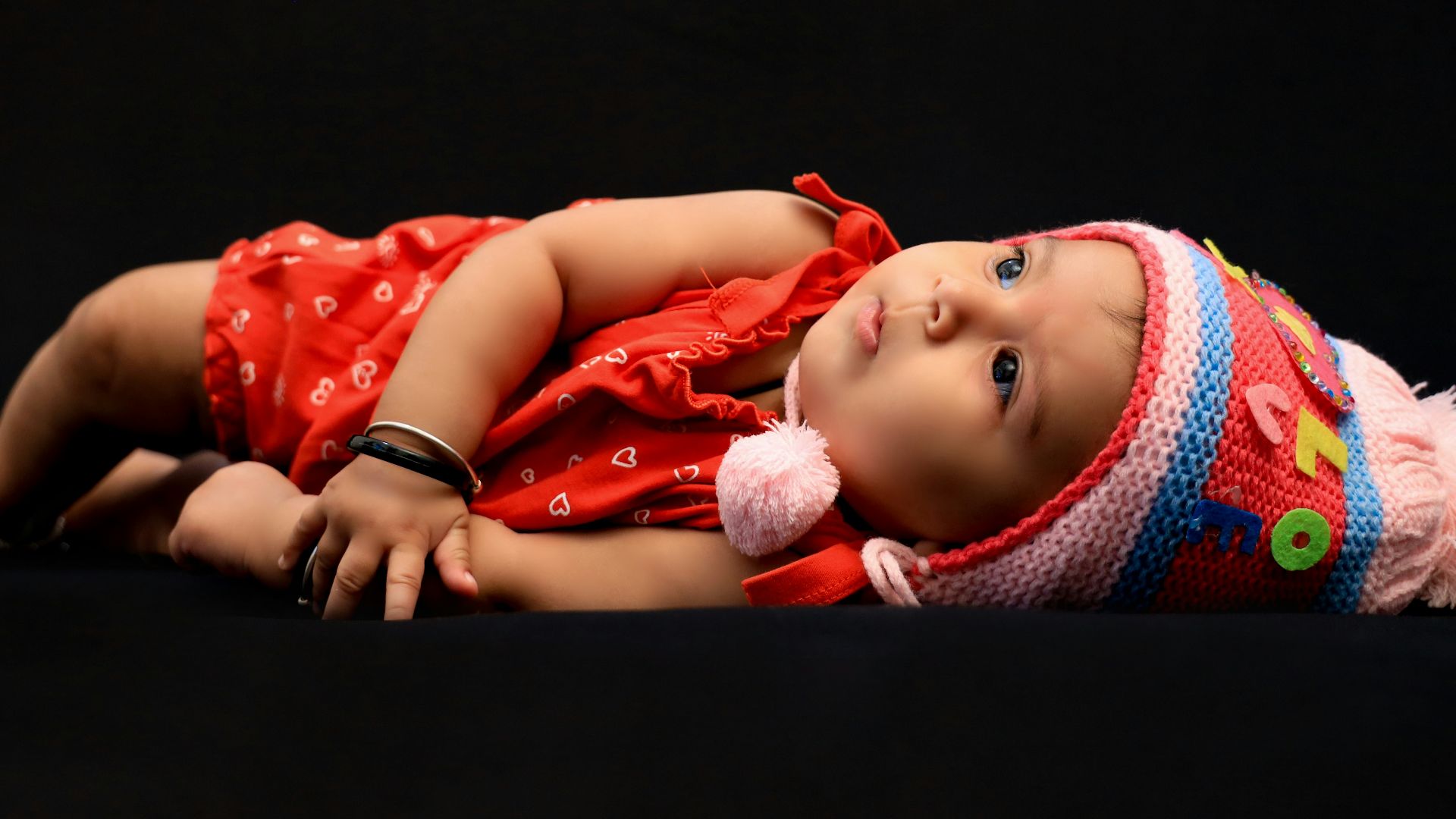 baby in red shirt lying on black textile