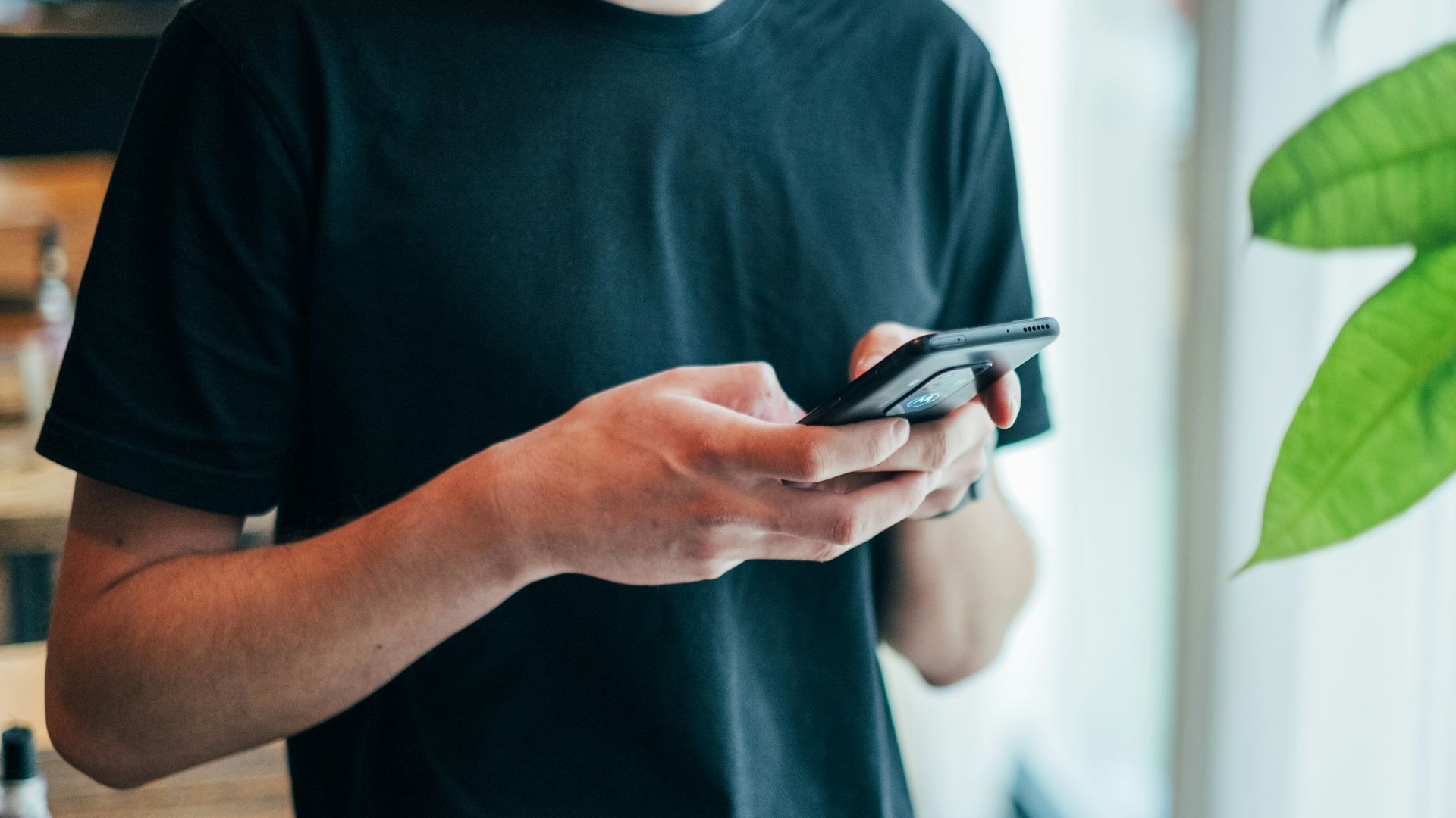 man in black crew-neck top using smartphone