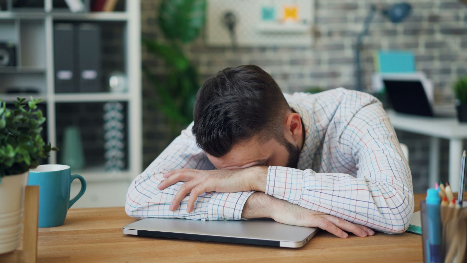 a man sitting at a desk with his head in his hands