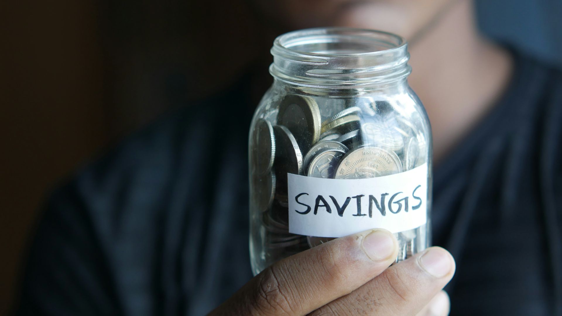 a man holding a jar with a savings label on it