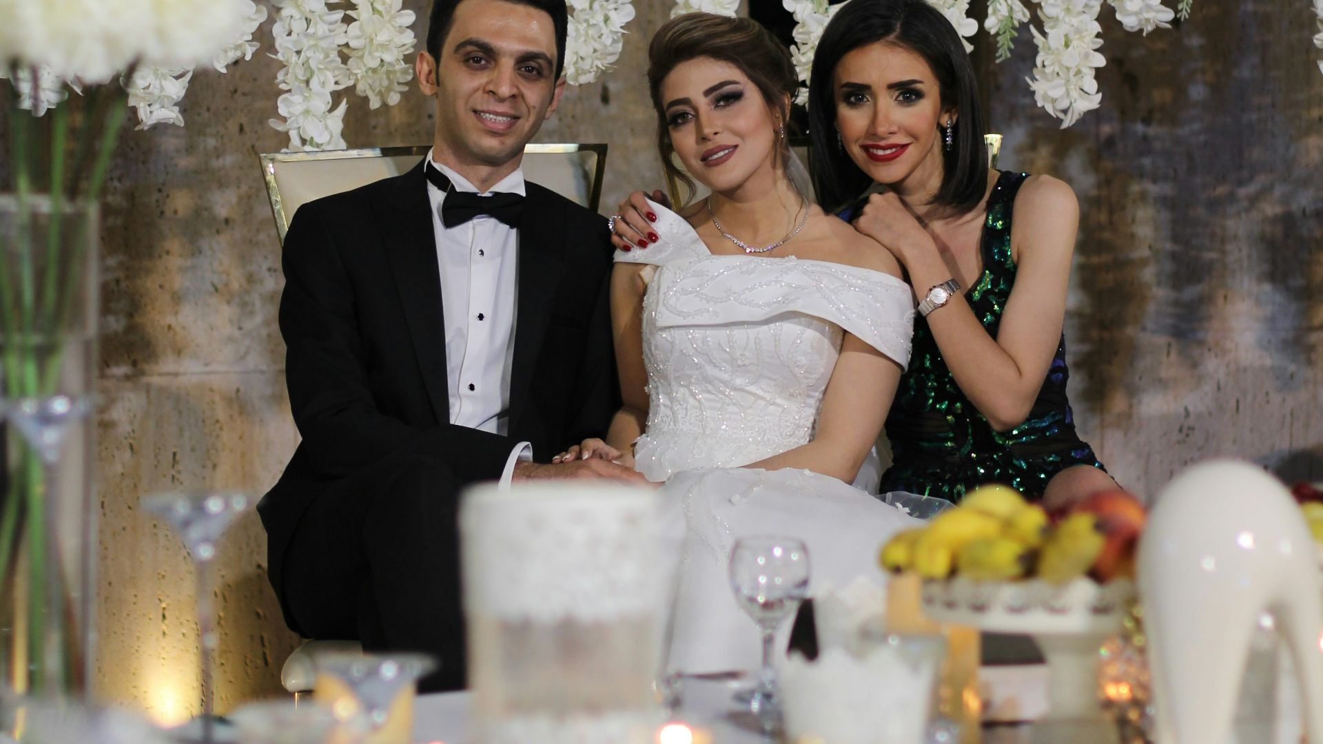 a man and a woman posing for a picture in front of a table with flowers