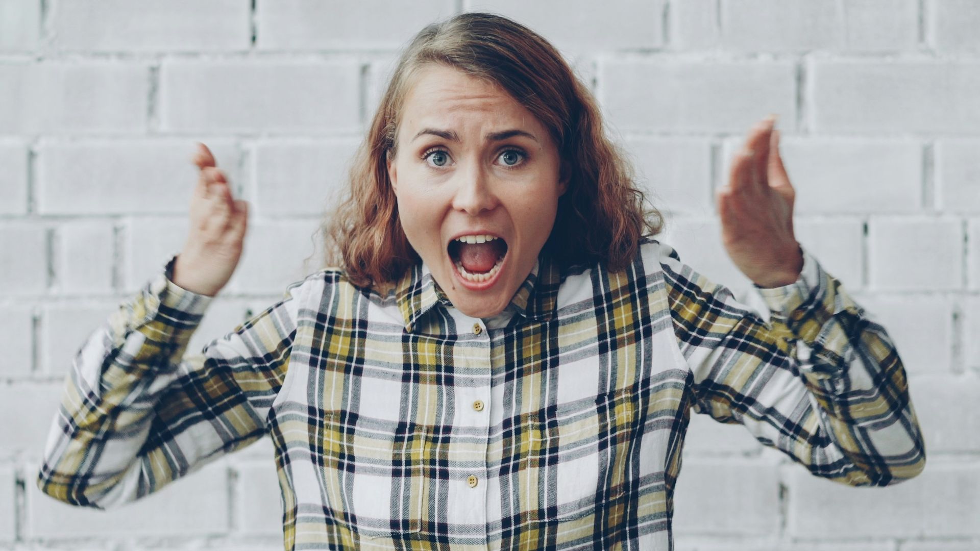 Woman with hands raised shouting in frustration.